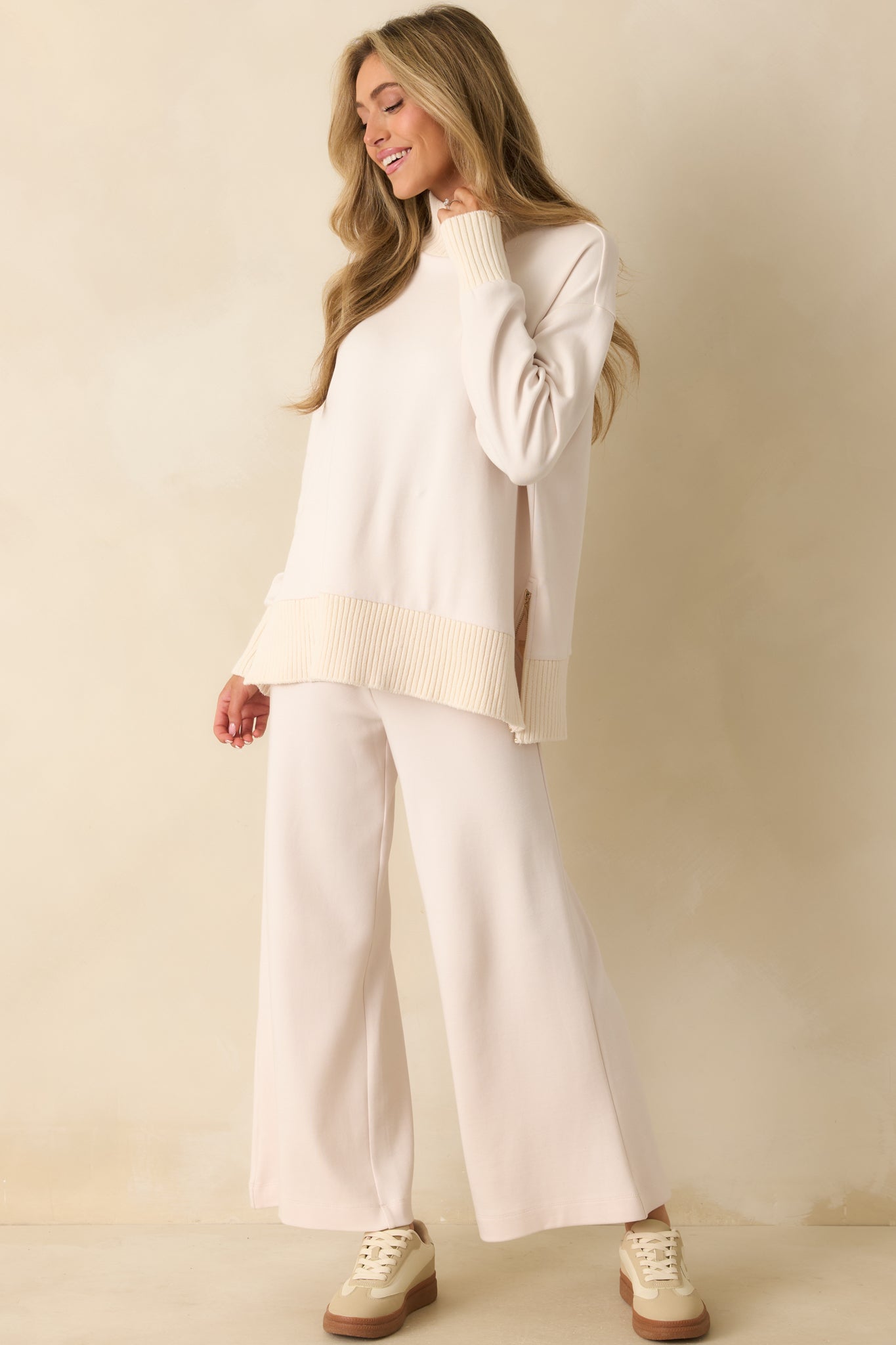 Ivory sweater with ribbed mock neckline, long sleeves, and a relaxed fit.