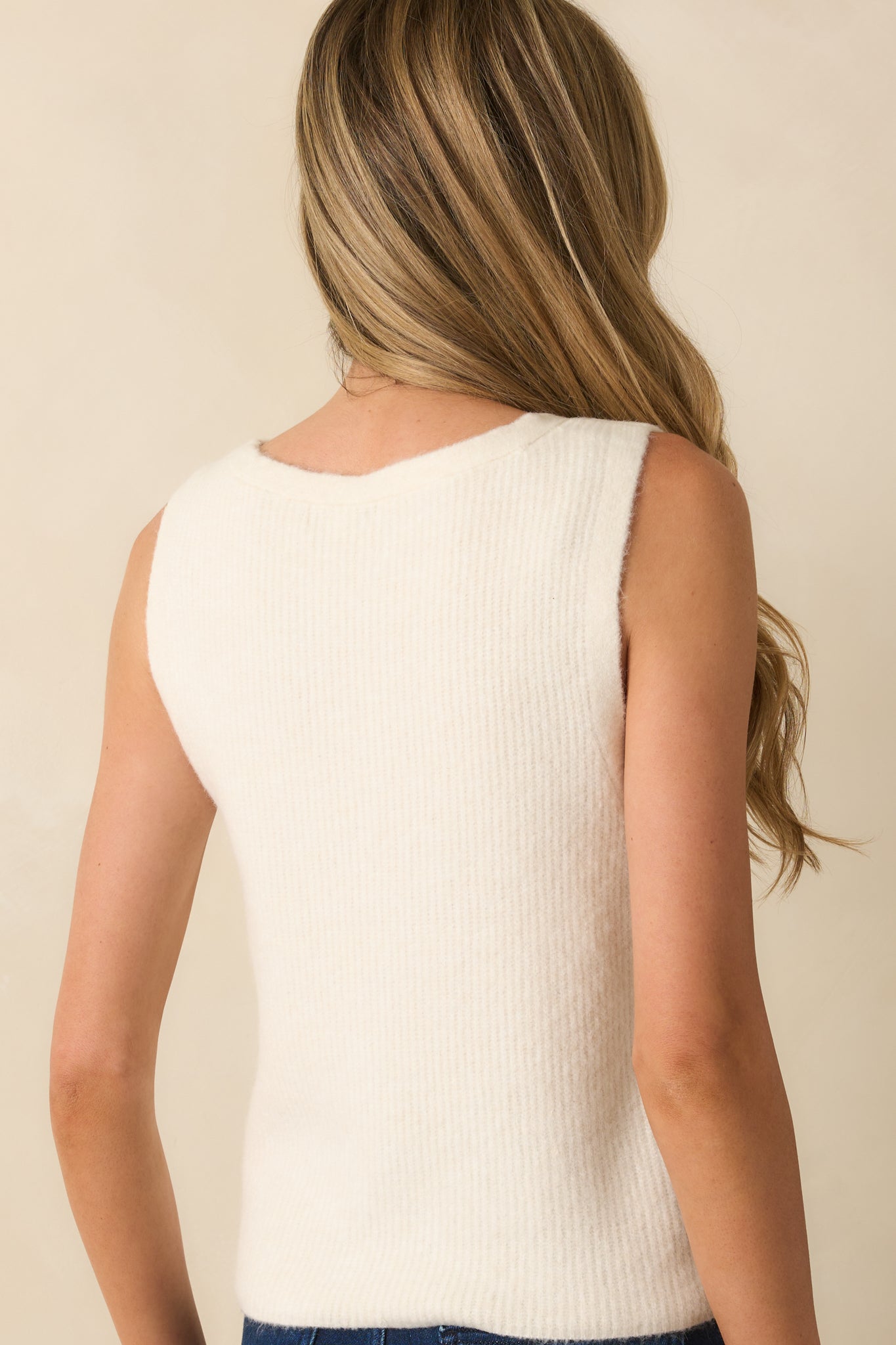 Rear view of the ivory sweater vest showing the ribbed hem and relaxed silhouette.