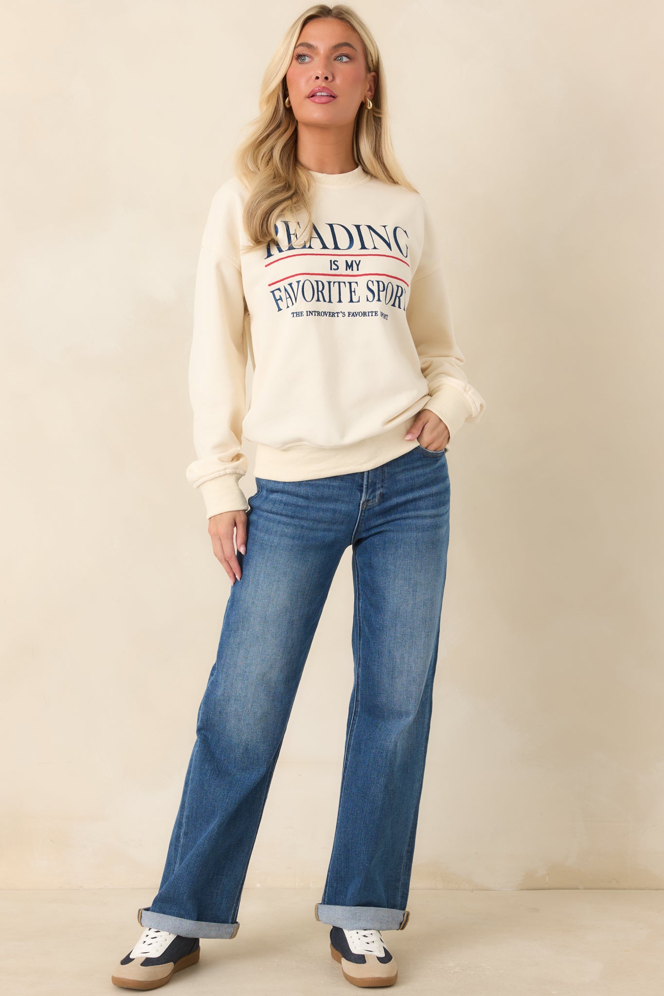 Ivory sweatshirt featuring embroidered navy and red lettering with the phrase “Reading Is My Favorite Sport” across the front.