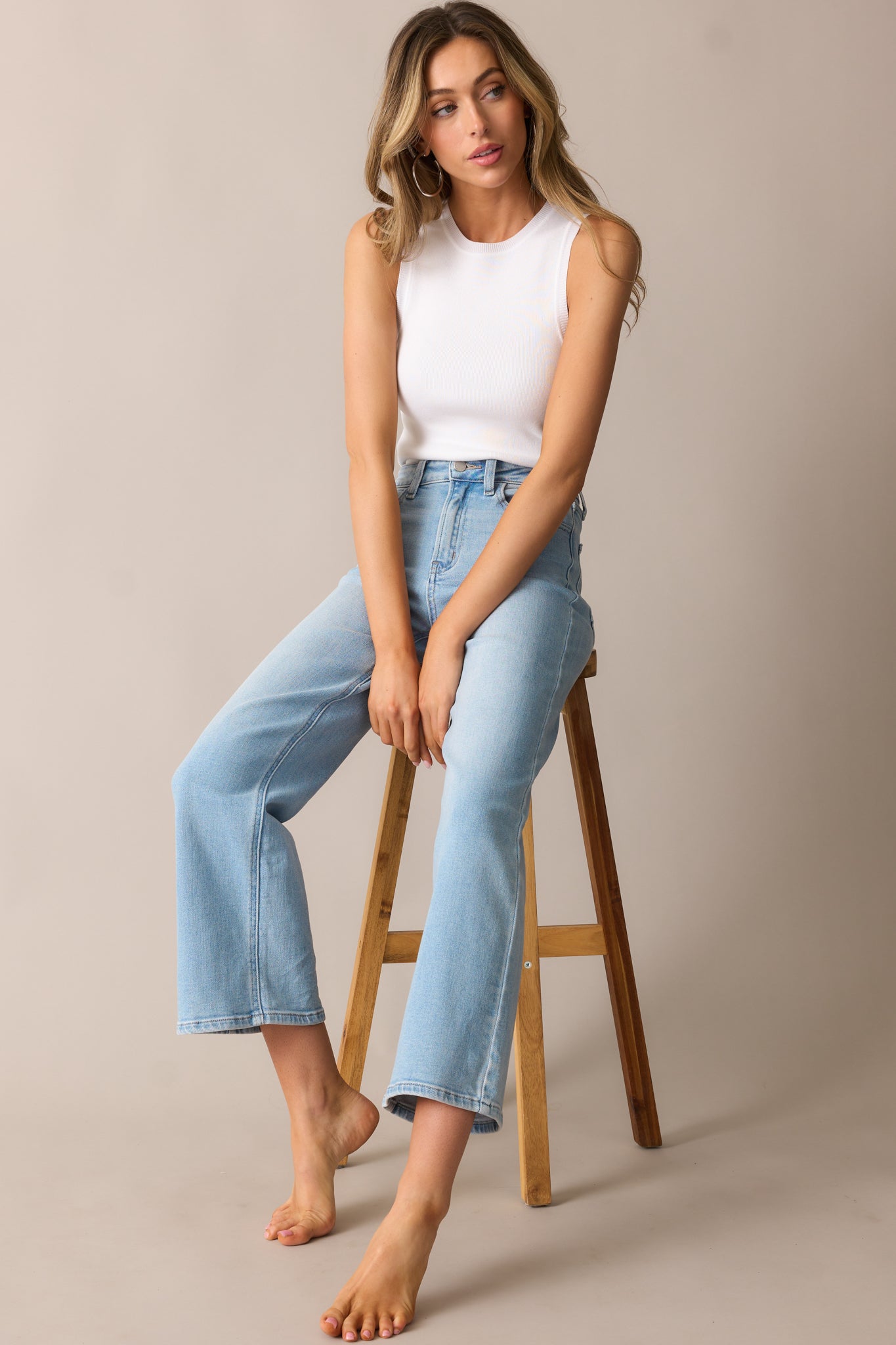 The ivory tank top with a crew neckline and ribbed fabric, naturally fitted over the torso with a split hem detail.