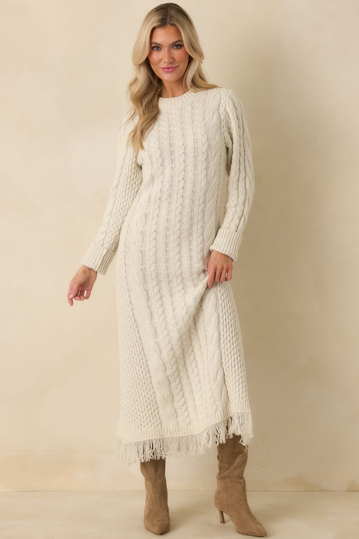 Textured ivory knit maxi dress featuring varied cable patterns, long sleeves, and movement-ready fringe trim.