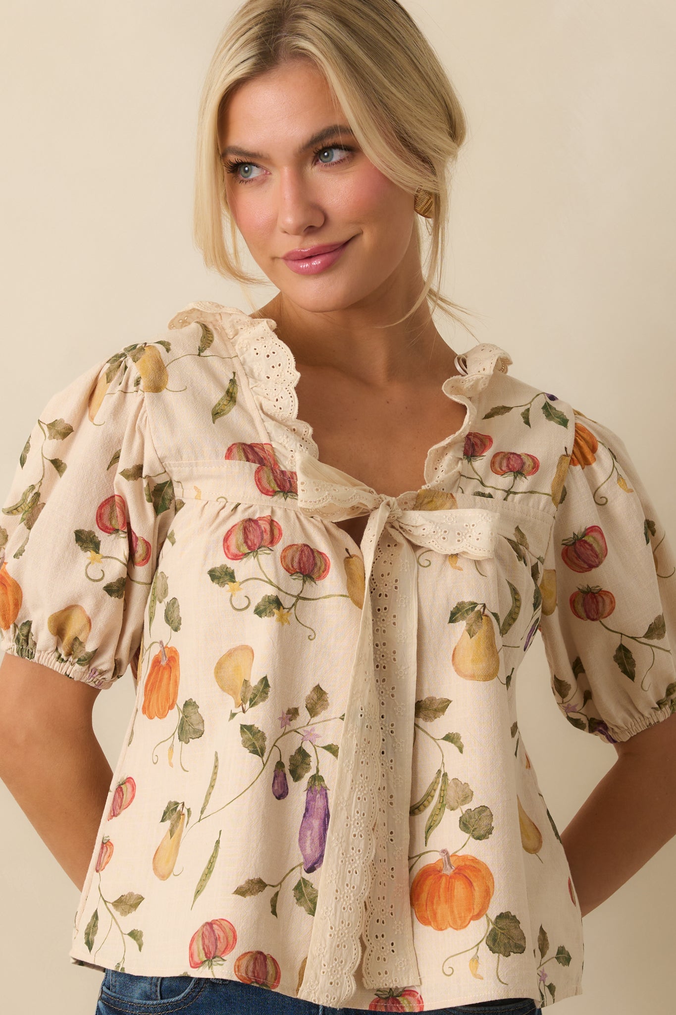 Cropped close front of ivory top focusing on puff sleeves and delicate self-tie closure.