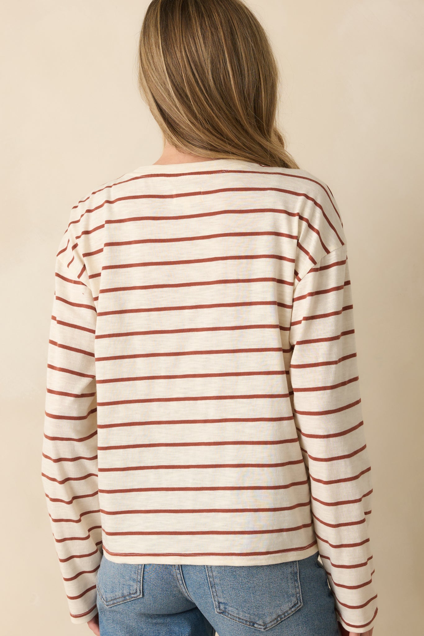 Back view of the top, showing cinnamon brown stripes across the ivory fabric and a relaxed fit.