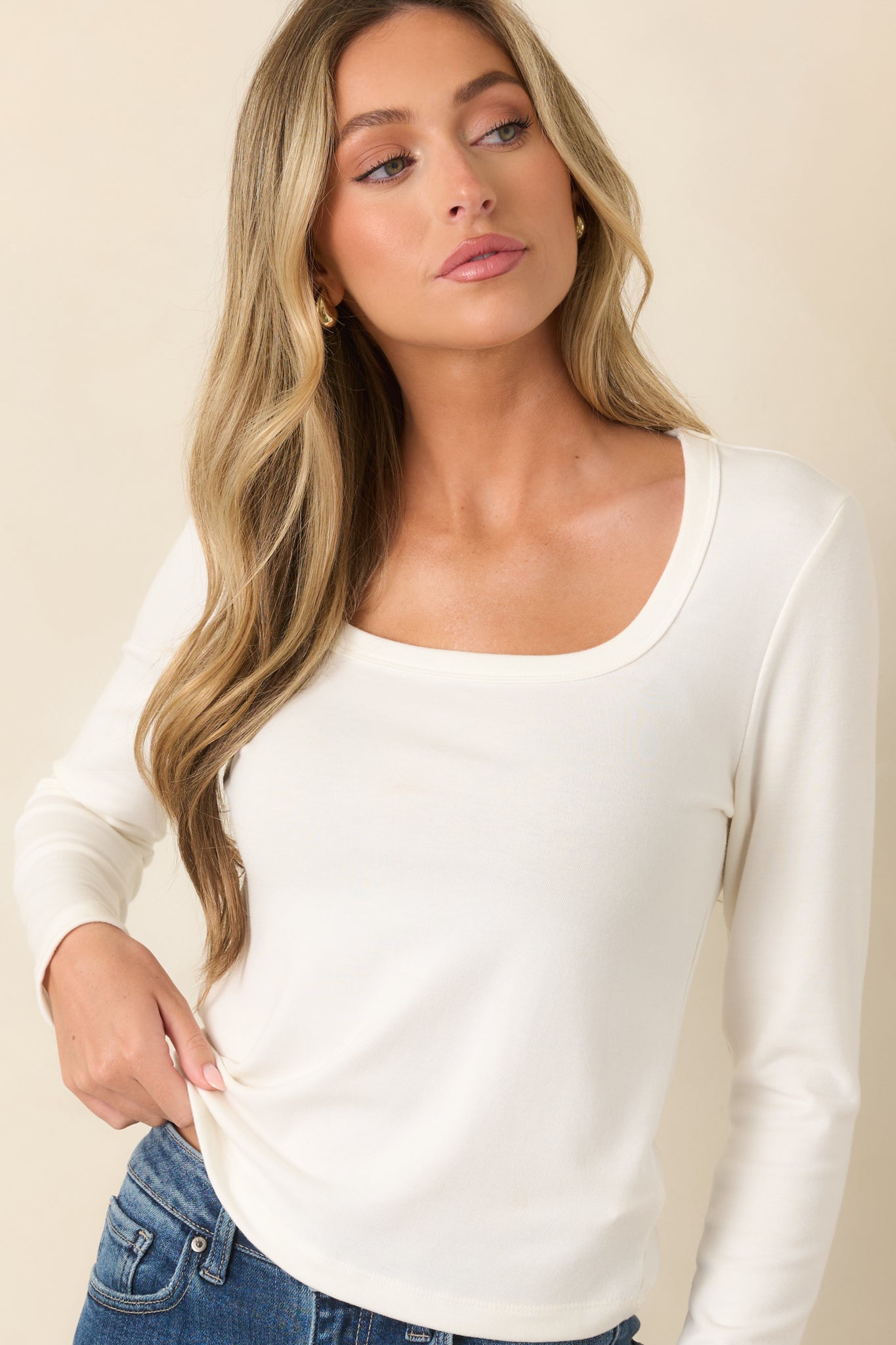 Close view of the ivory scoop neckline, soft fabric texture, and long sleeve design.