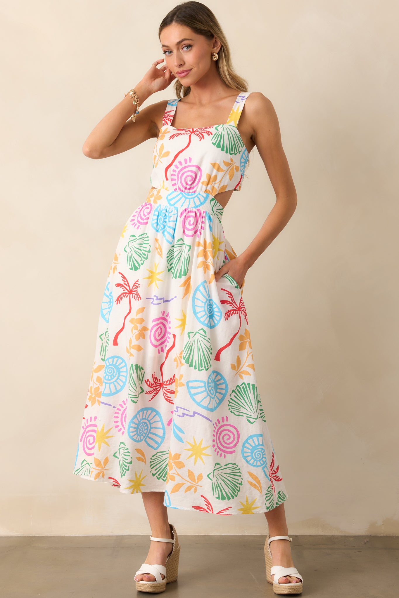 Ivory maxi dress adorned with a vibrant tropical print, featuring a square neckline and a flowing silhouette with functional pockets.