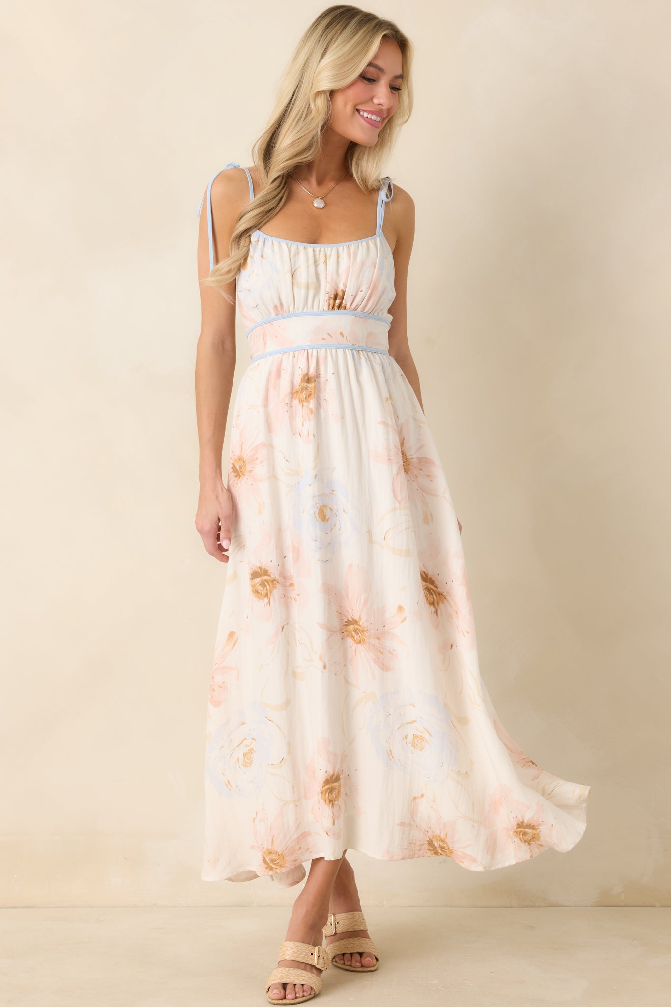 Ivory floral midi dress featuring watercolor-inspired blooms, adjustable tie straps, and a softly flowing skirt.