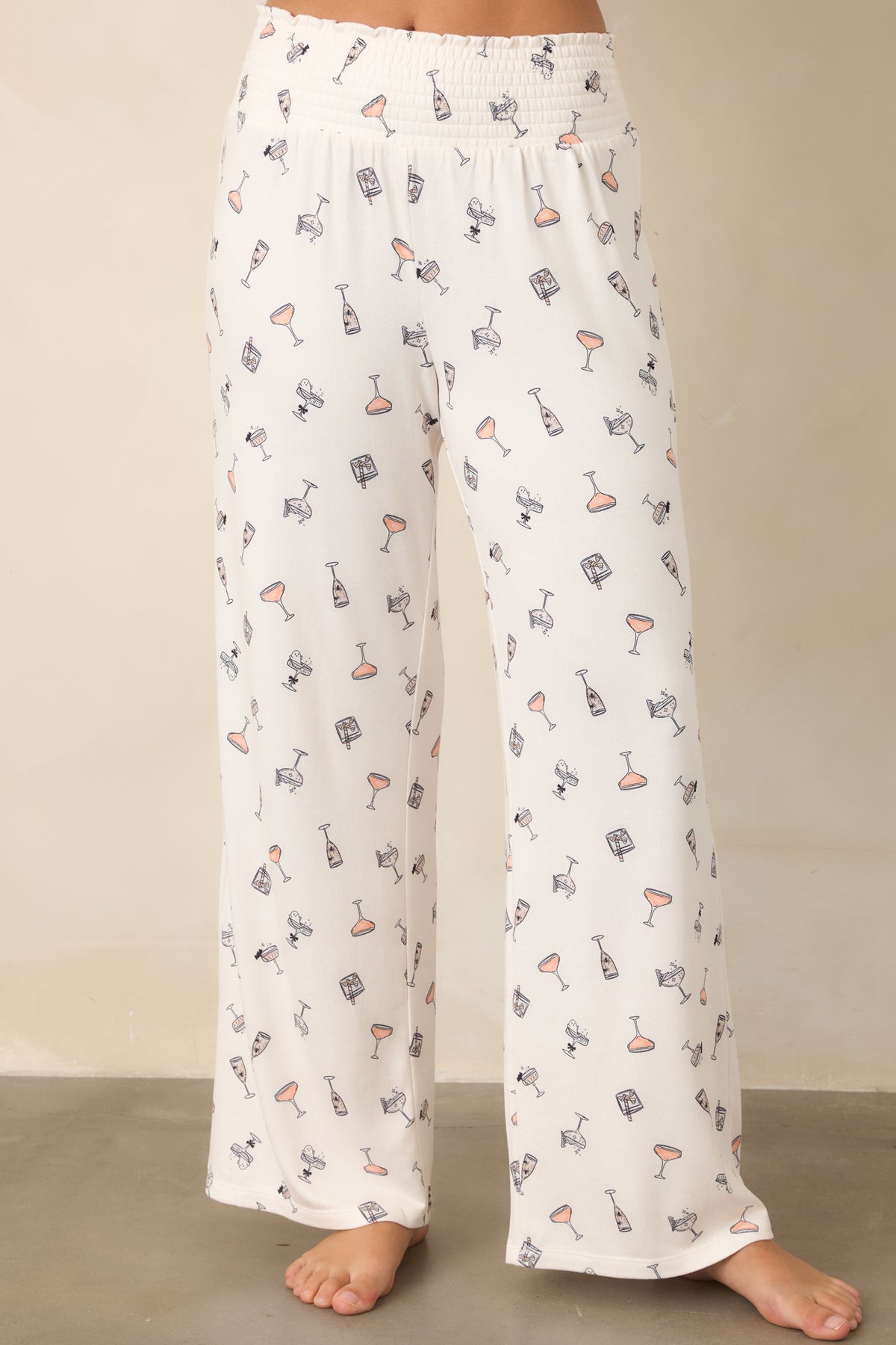 Ivory wide-leg pants with an allover cocktail print, delicate spooky accents, and a wide smocked waistband.