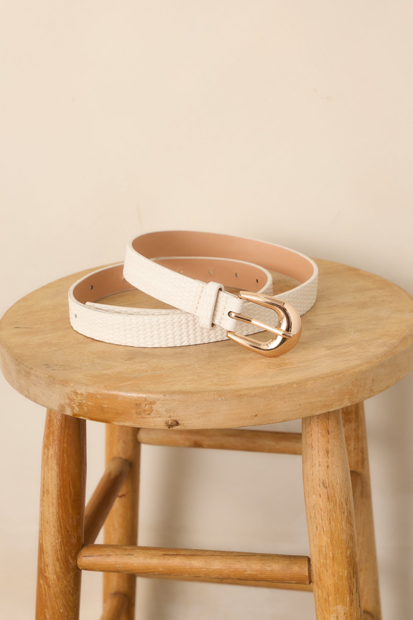 Ivory woven-texture belt highlighting the clean strap edges, subtle dimensional finish, and refined gold-tone buckle hardware.