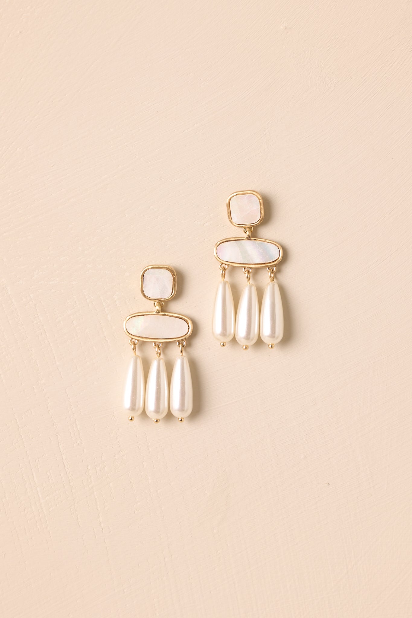 Front view of earrings highlighting gold bezel settings and ivory pearlescent details.