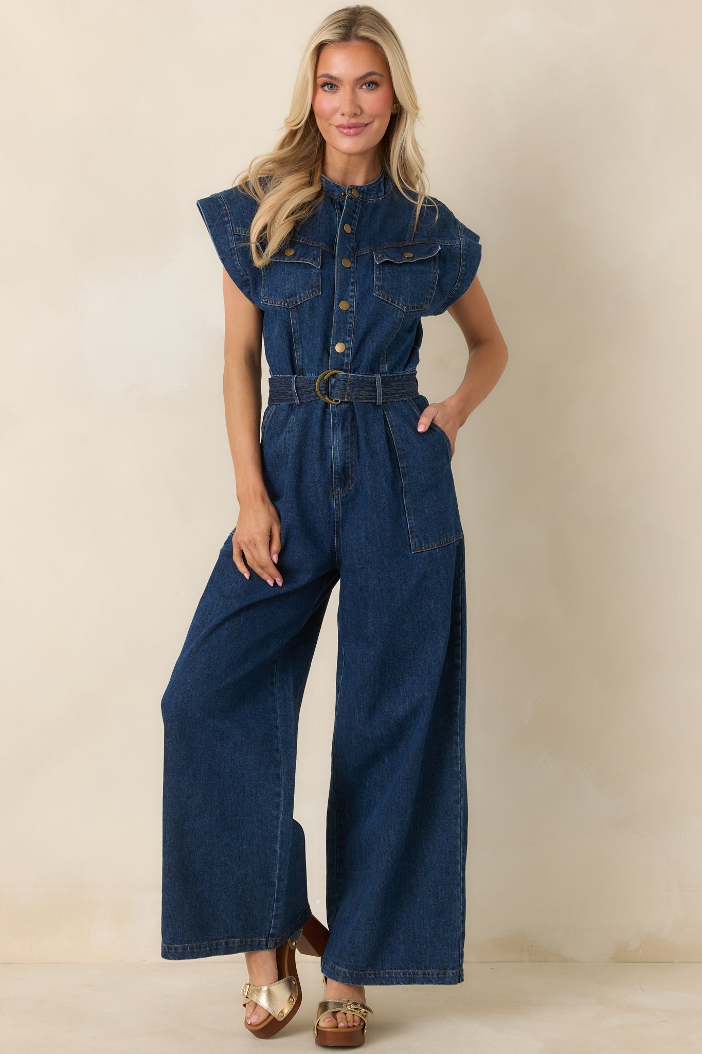 Structured jumpsuit with snap-button placket, cap-style sleeves, removable belt, and flowing wide legs.