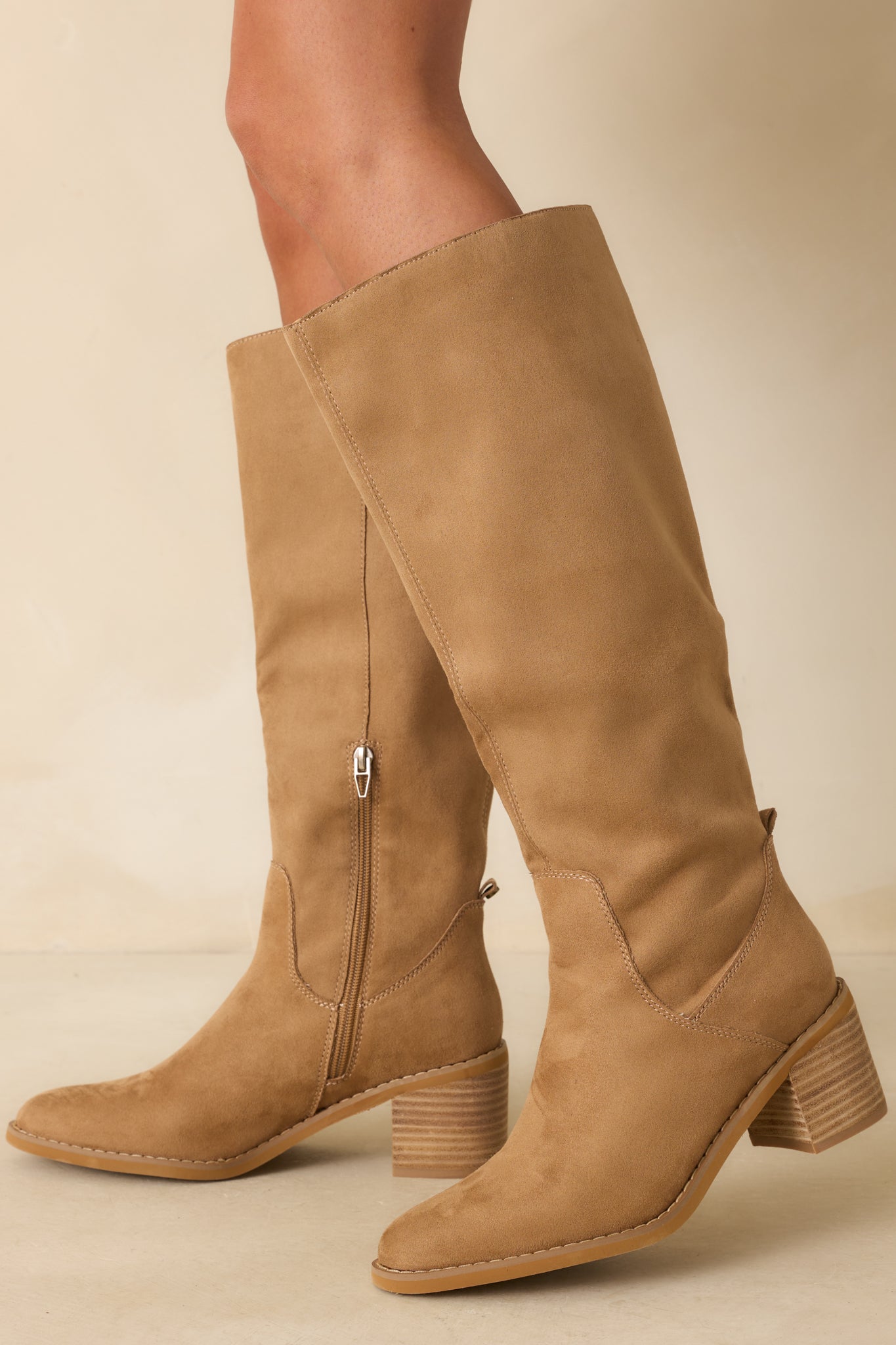 Side angle shows sleek knee-high silhouette with almond toe and zipper closure.