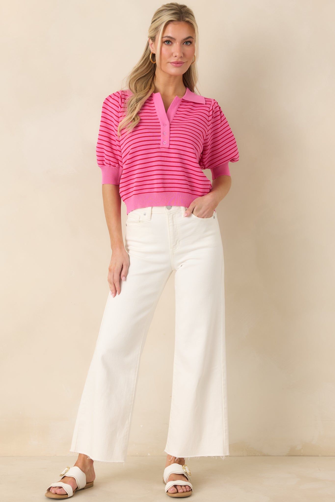 Knit polo top in pink stripes with a collared neckline, partial button closure, and subtle puff sleeve detailing.