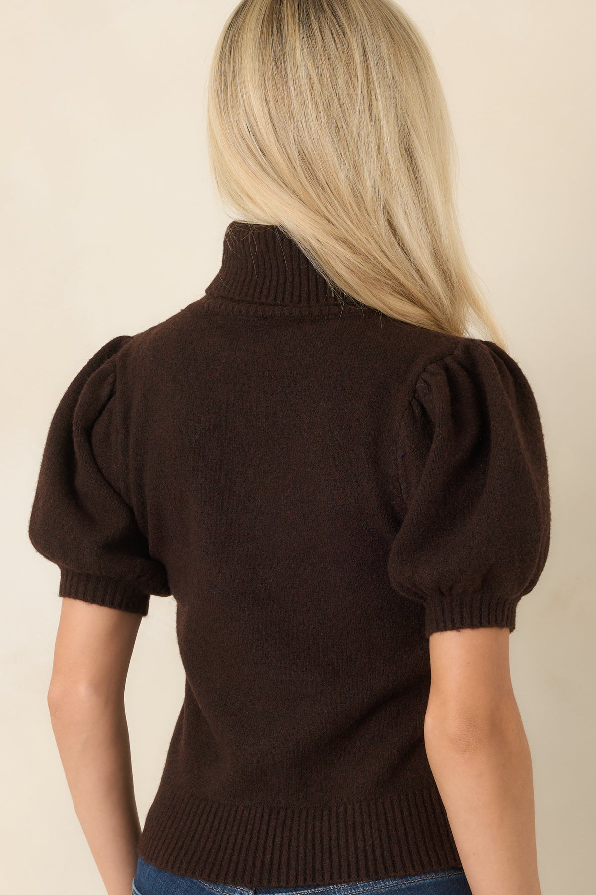 Rear view of the knit turtleneck sweater featuring a smooth back, softly gathered sleeves, fitted ribbed cuffs, and a ribbed hem for a polished finish.