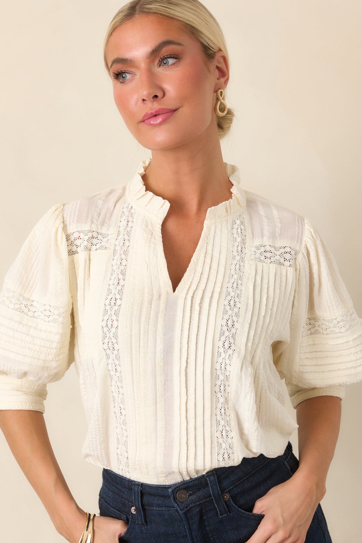 Voluminous blouse with three-quarter balloon sleeves, lace accents, vertical pleats, and a softly feminine ruffled neckline.