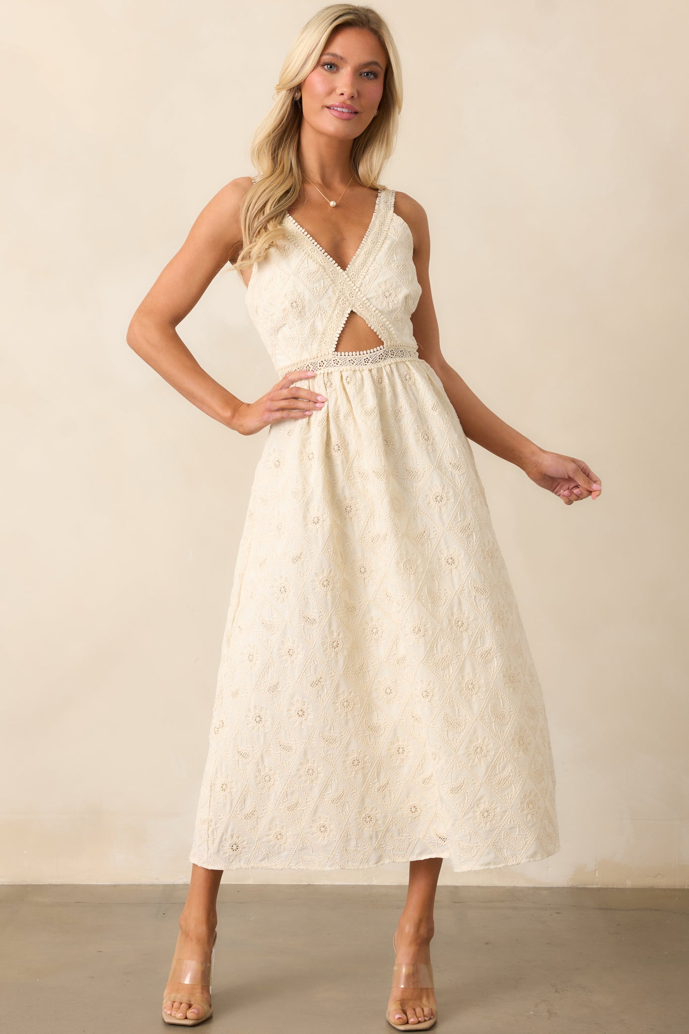 A romantic ivory dress with lace embroidery, a v-neckline, and a bodice cutout, offering a flattering fit with its adjustable straps and feminine design.