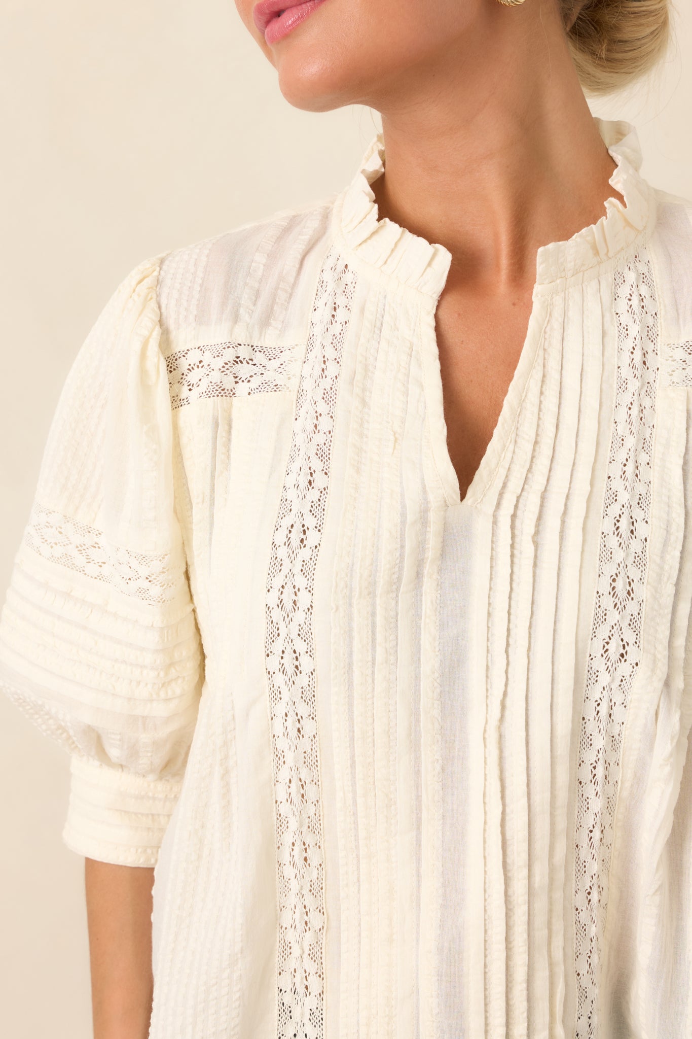 Close-up of the textured blouse highlighting the delicate lace panels, vertical pleats, and softly ruffled neckline.