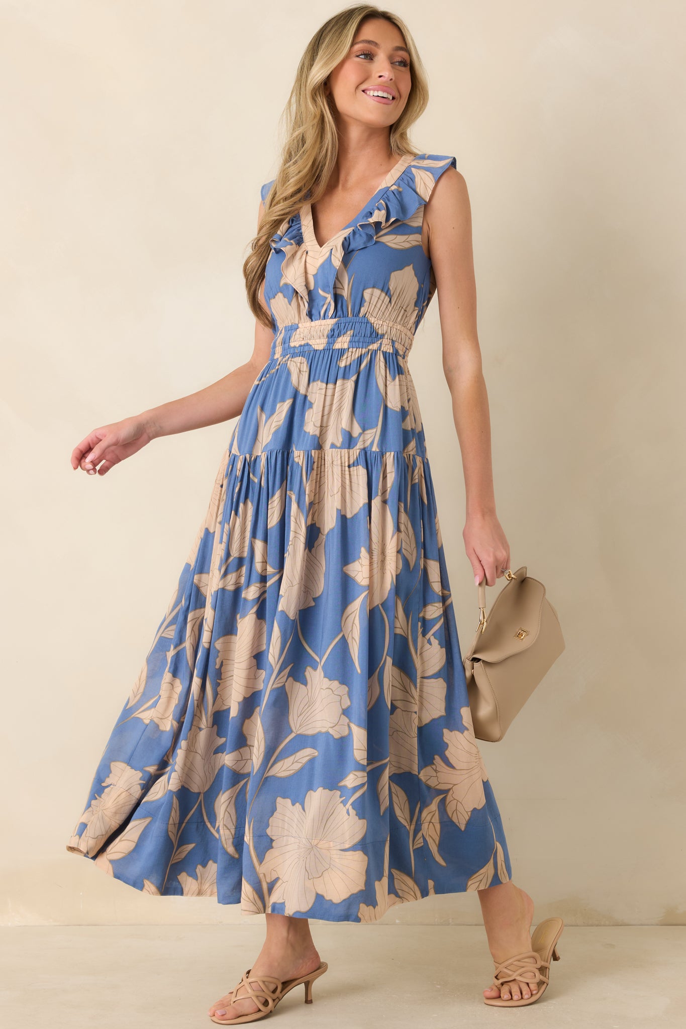 Lake blue floral maxi dress featuring oversized blooming florals, a ruffle-trimmed V-neckline, sleeveless design, smocked waistband, and tiered skirt.