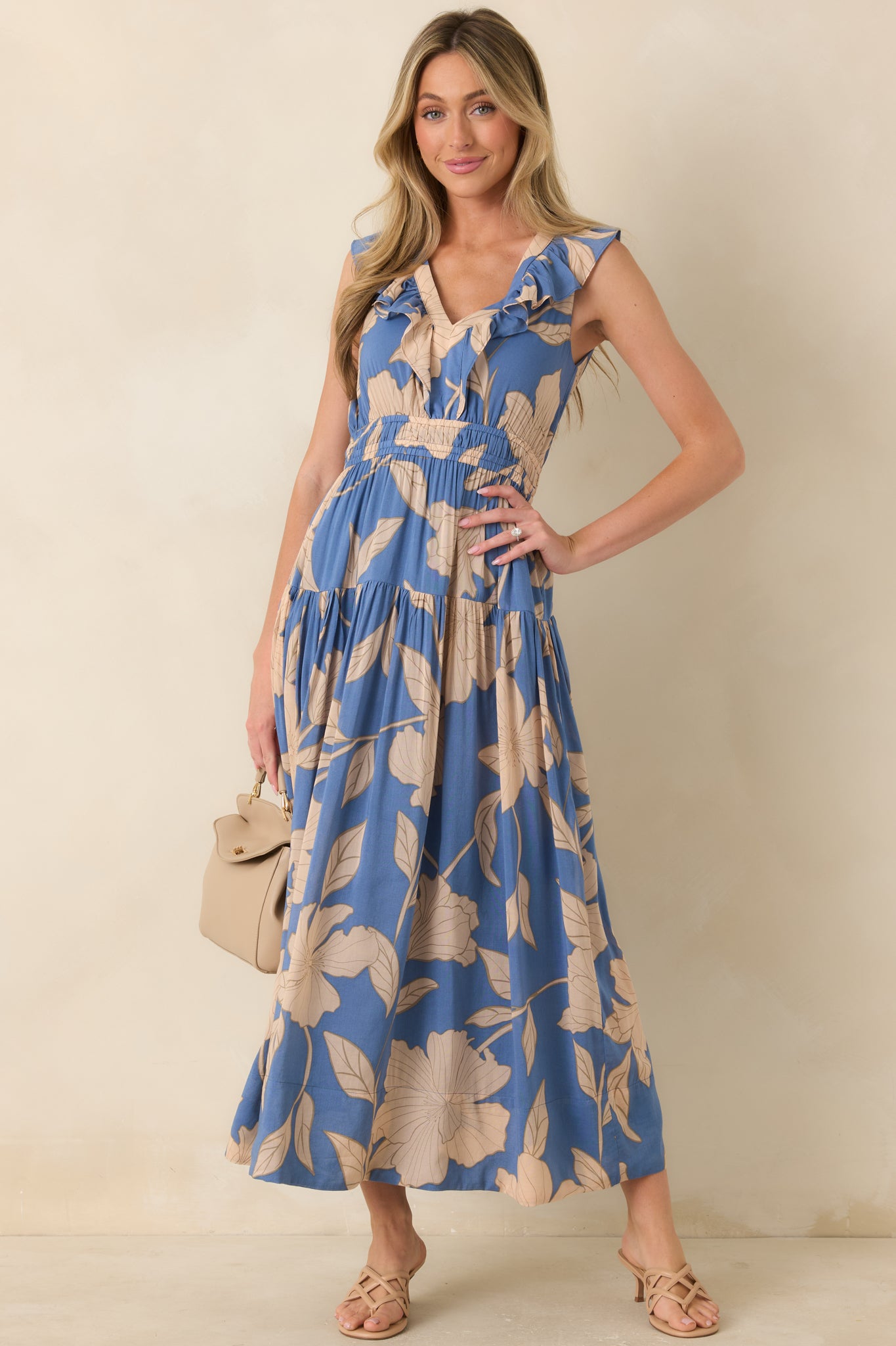 Floral maxi dress with a soft lake blue backdrop, oversized floral print, sleeveless construction, and flattering defined waistline.