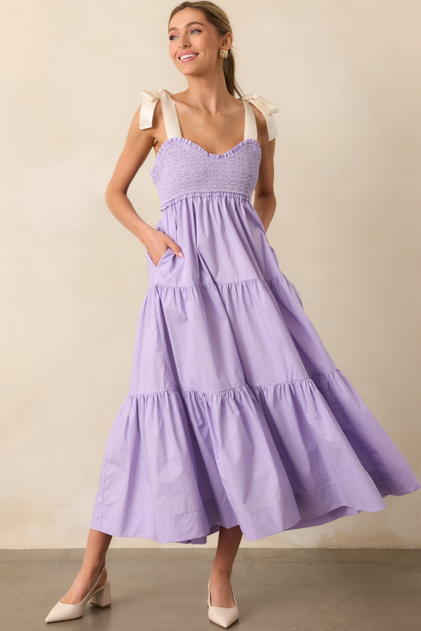 A charming lavender midi dress featuring a sweetheart neckline, embroidered smocking, and functional pockets for added convenience.