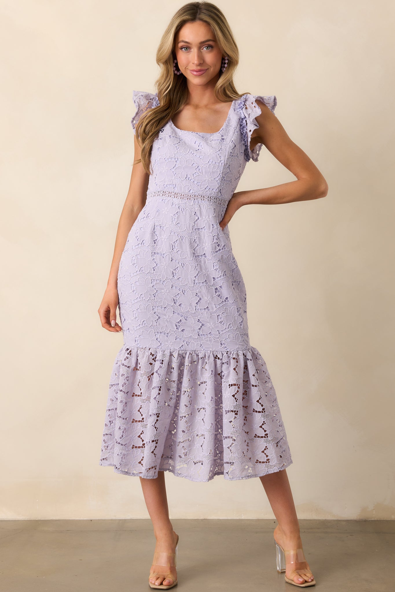A lavender midi dress with a scoop neckline and floral embroidered overlay, elegantly flowing with a tiered skirt.