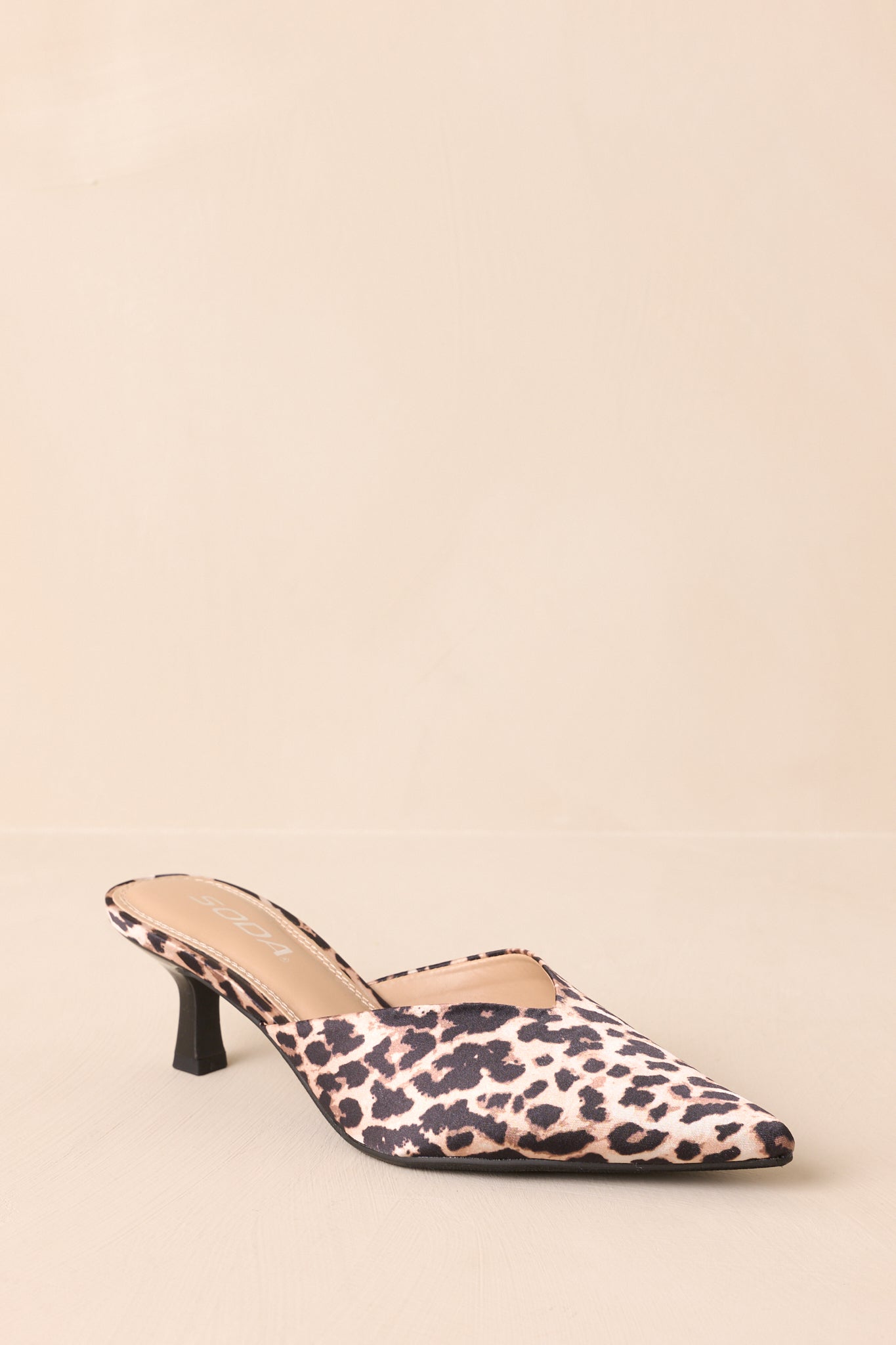 Leopard heels displayed on beige backdrop with toe pointing forward.
