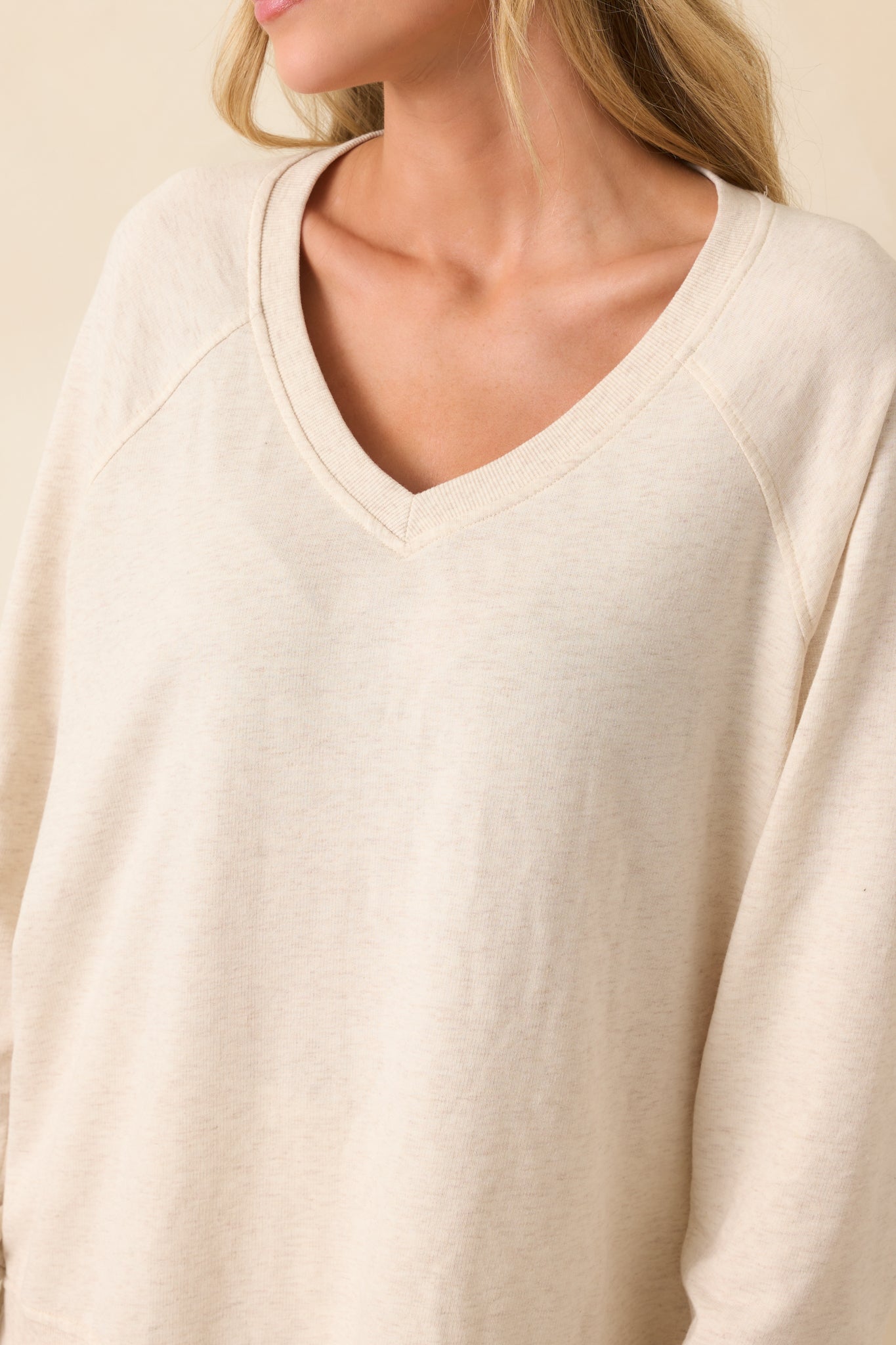 Close-up detail of the sweatshirt showing the v-neckline stitching and fine ribbed trim along the collar.
