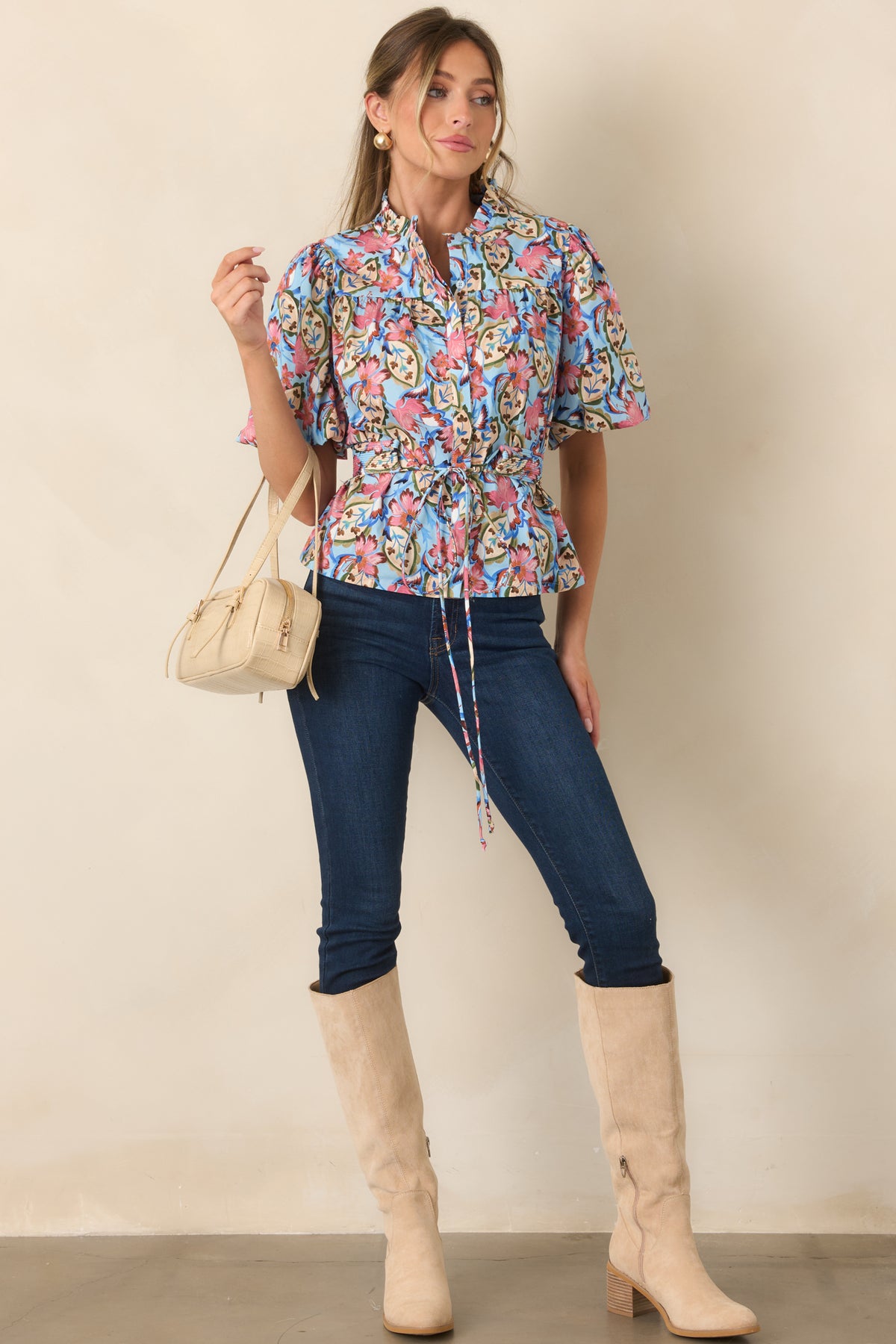 Light blue blouse showcasing pink botanical blooms, a ruffled collar, gathered shoulders, and short sleeves.