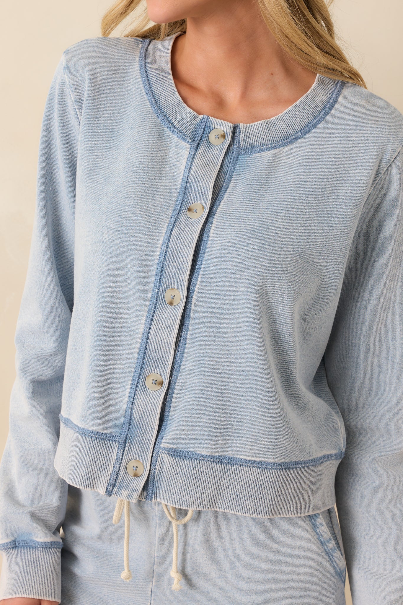 Zoomed-in image showing the knit fabric texture, stitching around the neckline, and small functional buttons.