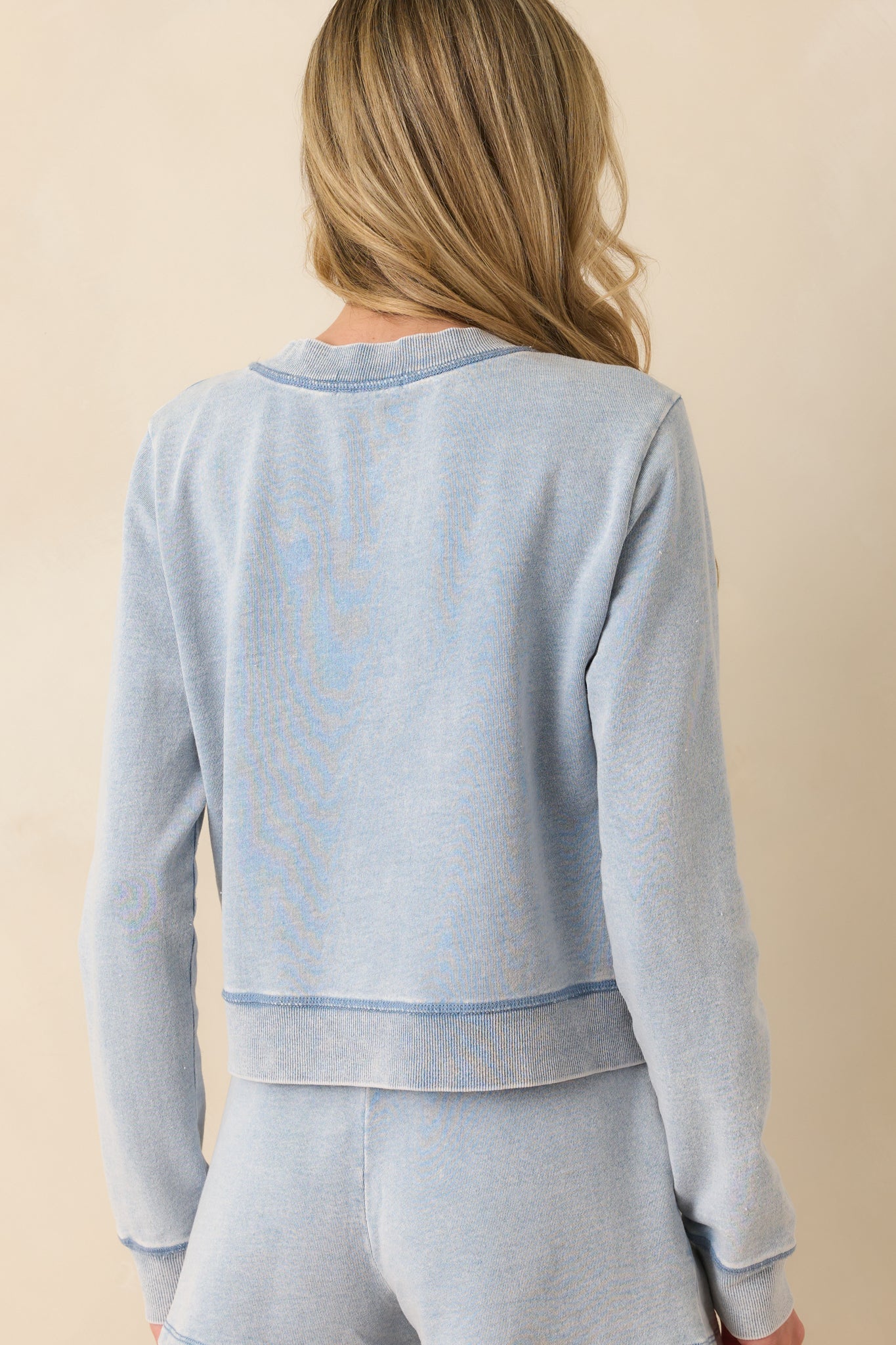 A view from behind showing the long sleeves, slightly cropped length, and smooth, even knit of the light blue cardigan.