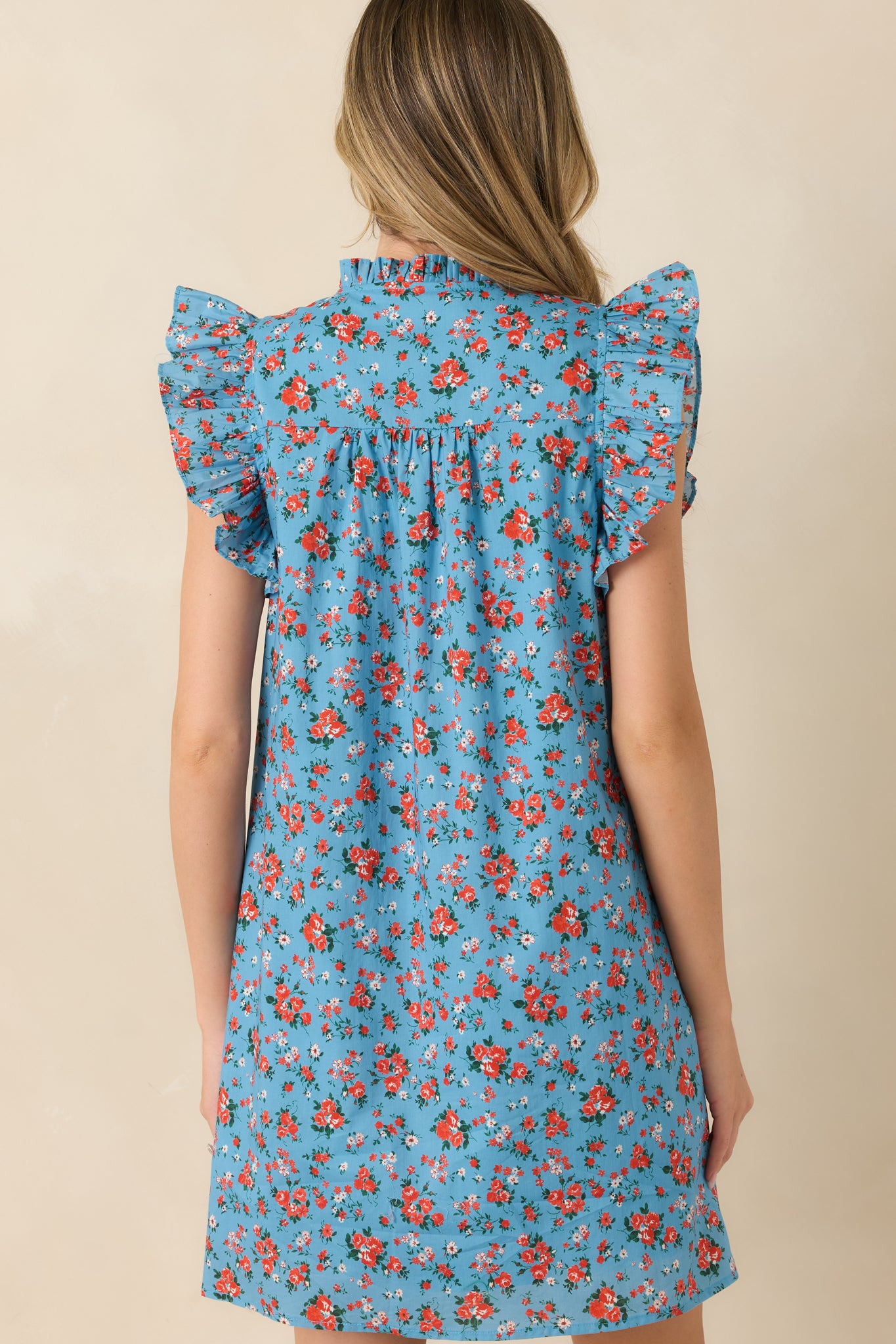 Rear view of the light blue floral cotton mini dress featuring flutter sleeves and a relaxed swing silhouette.