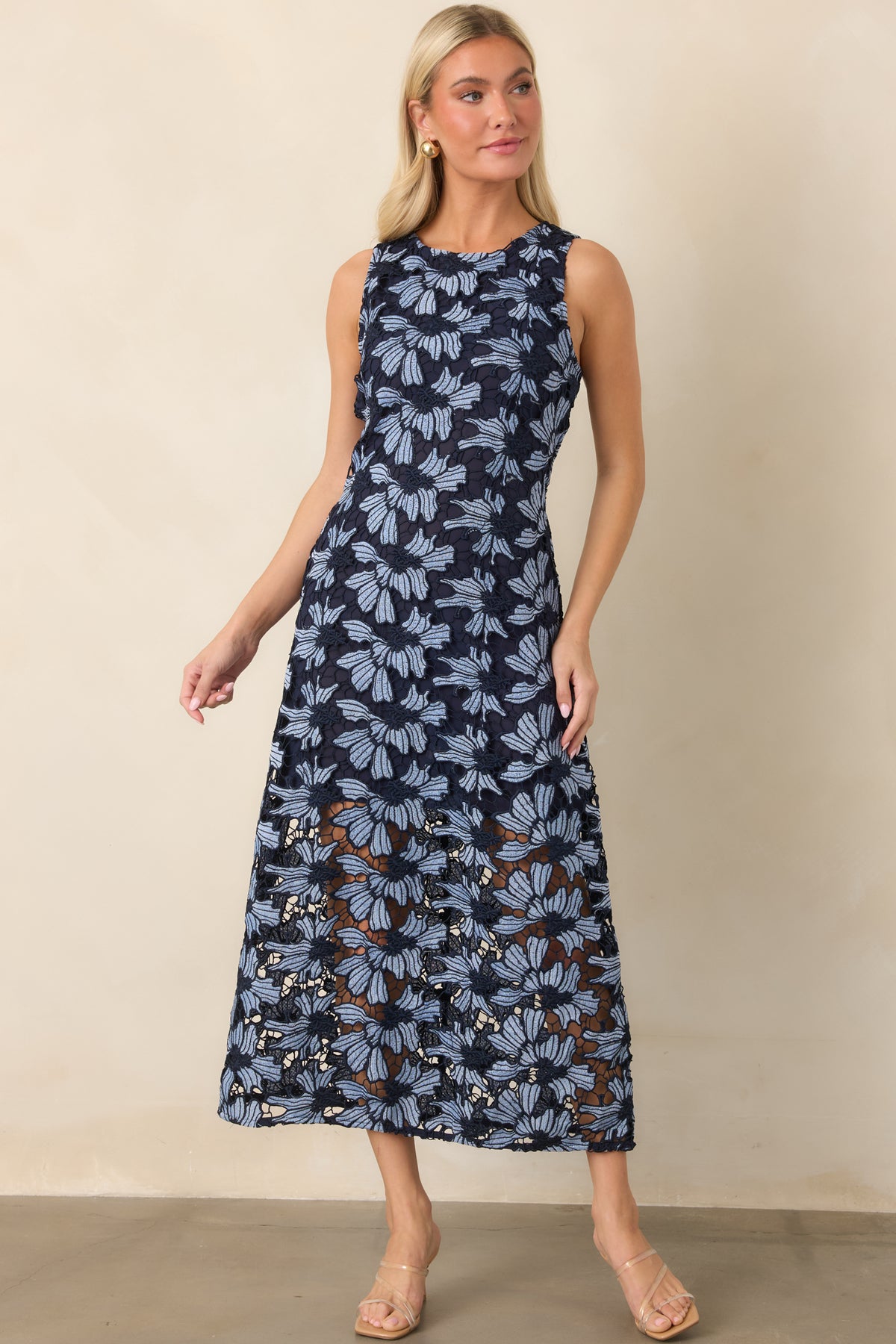 Light blue floral dress featuring oversized navy-outlined blooms, a rounded neckline, sleeveless design, and gently flared skirt.