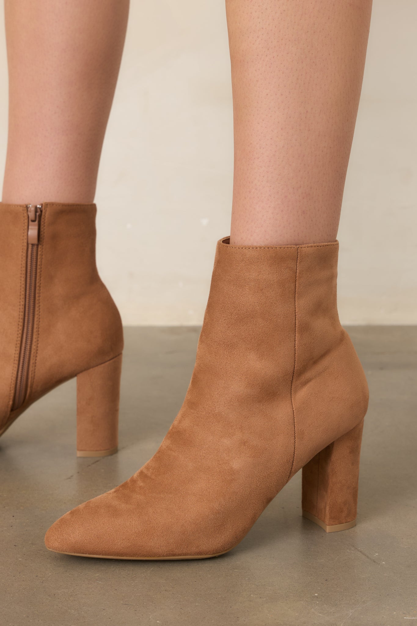 Light golden brown ankle boots with pointed toes, sleek faux suede uppers, and clean outer seam accents extending along the sides.