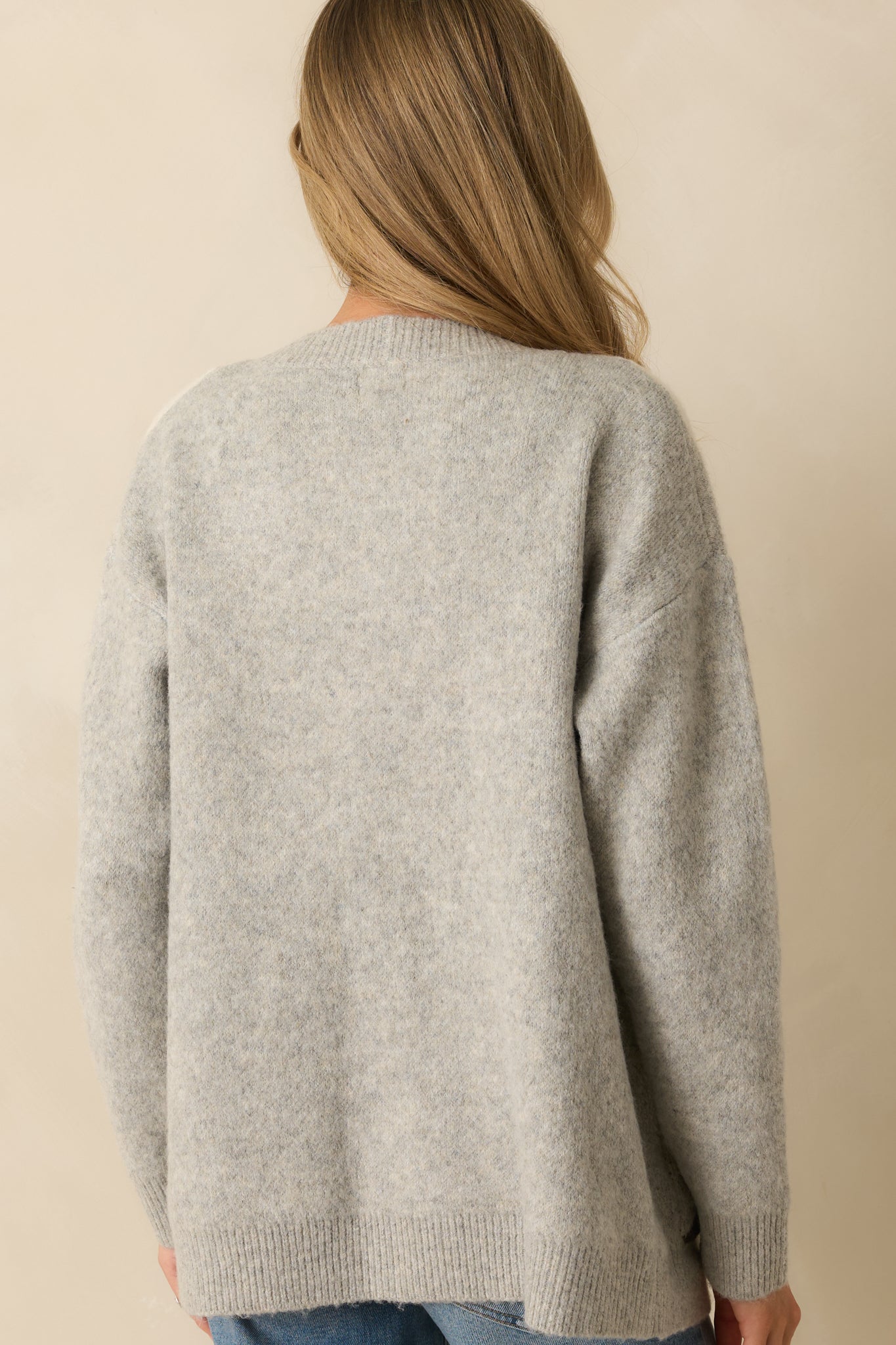 A back view of the light grey cardigan featuring a solid light grey knit fabric with ribbed hems and relaxed drape.