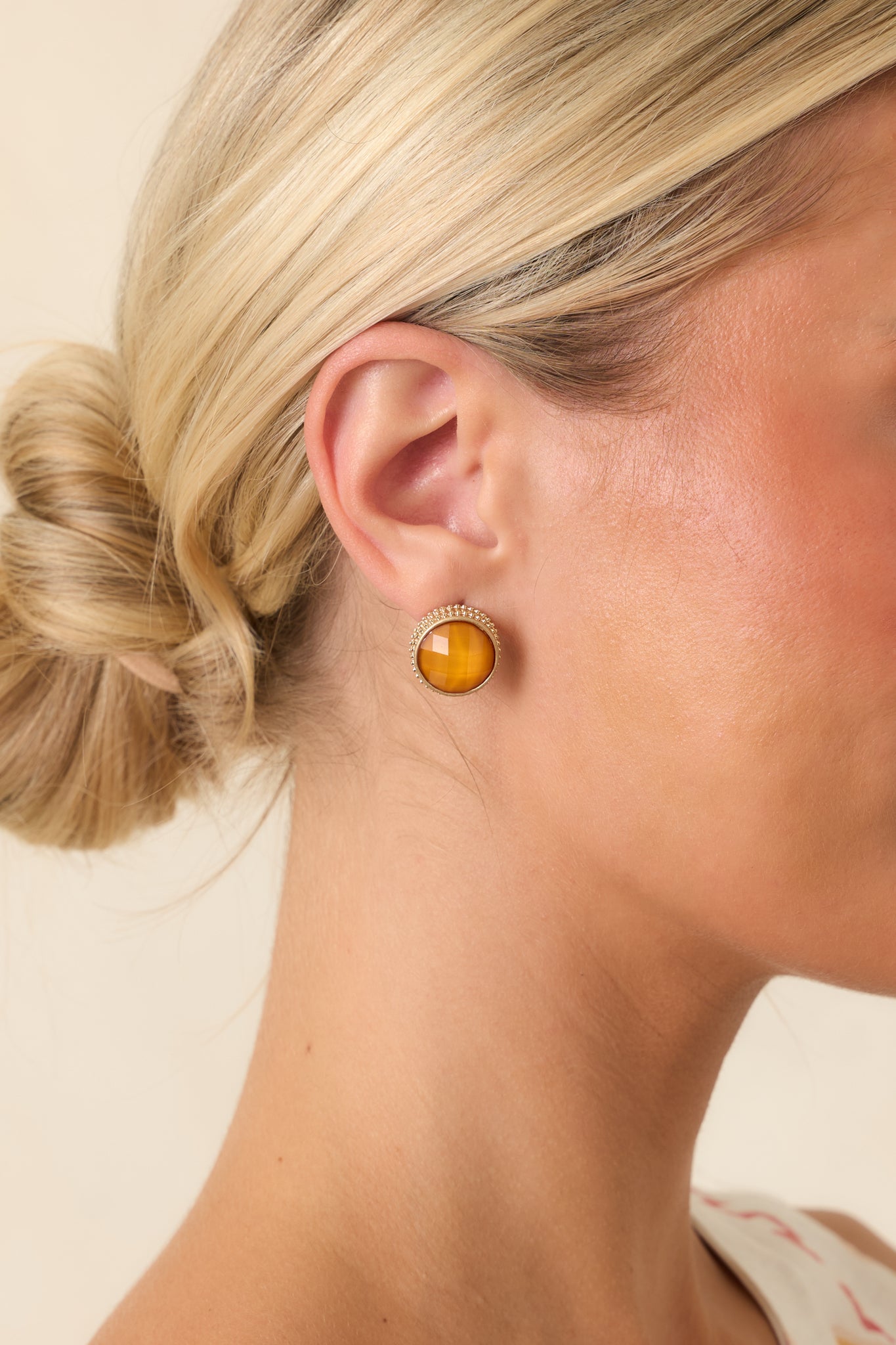 Light orange faceted stone stud earrings featuring a delicate gold halo setting.