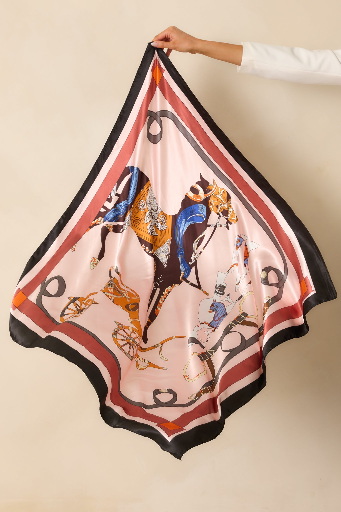 Light pink satin square scarf with horse and carriage print and multicolor accents framed by a striped border.