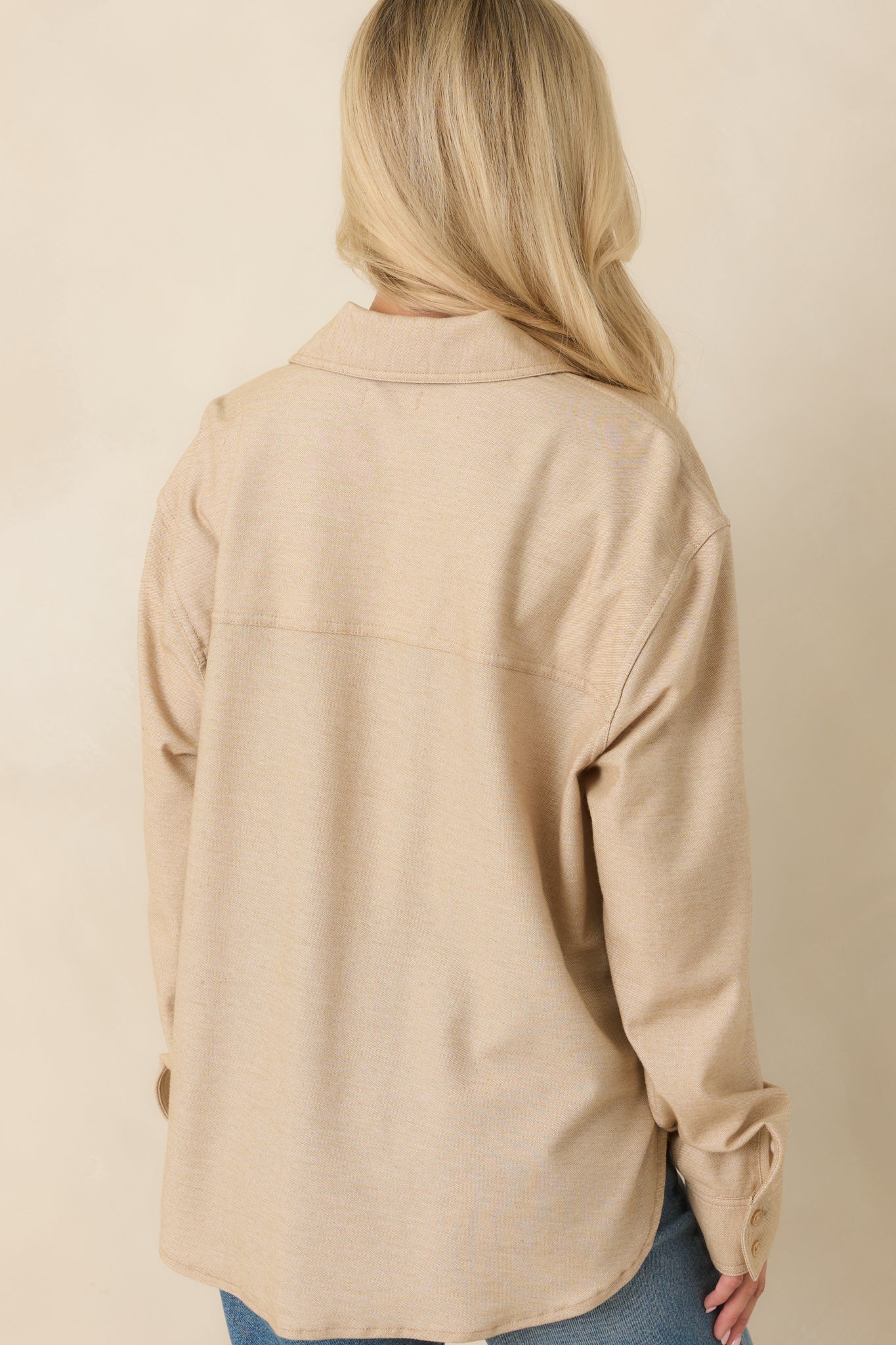 Rear view of the light toffee shirt showcasing the relaxed fit, long sleeves, and softly draped curved hem.