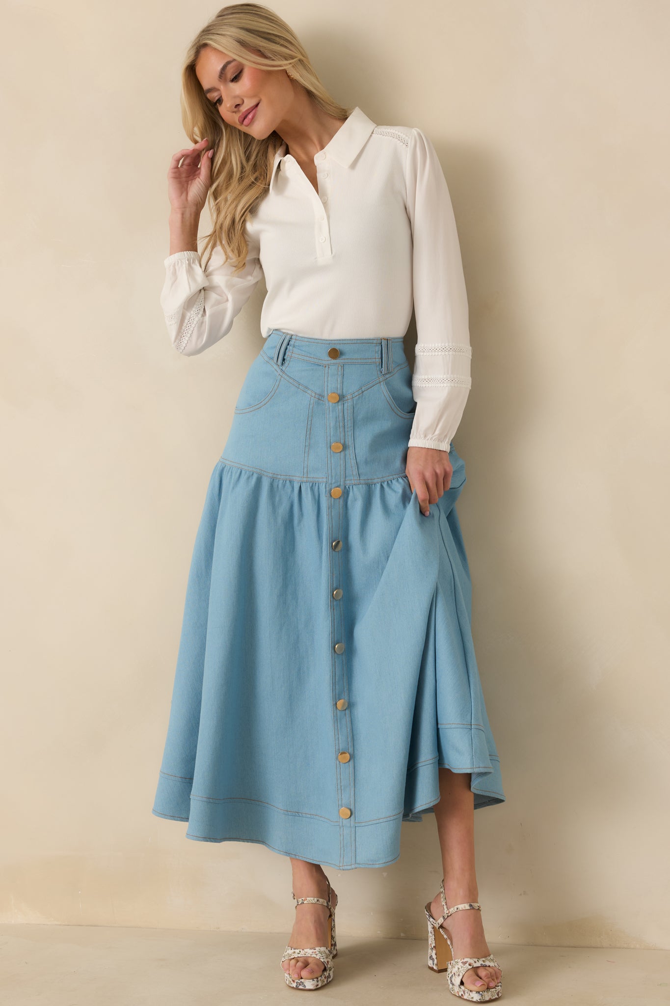 Light wash denim maxi skirt with high-rise fit, button-front closure, tiered panels, and flowing wide hem.