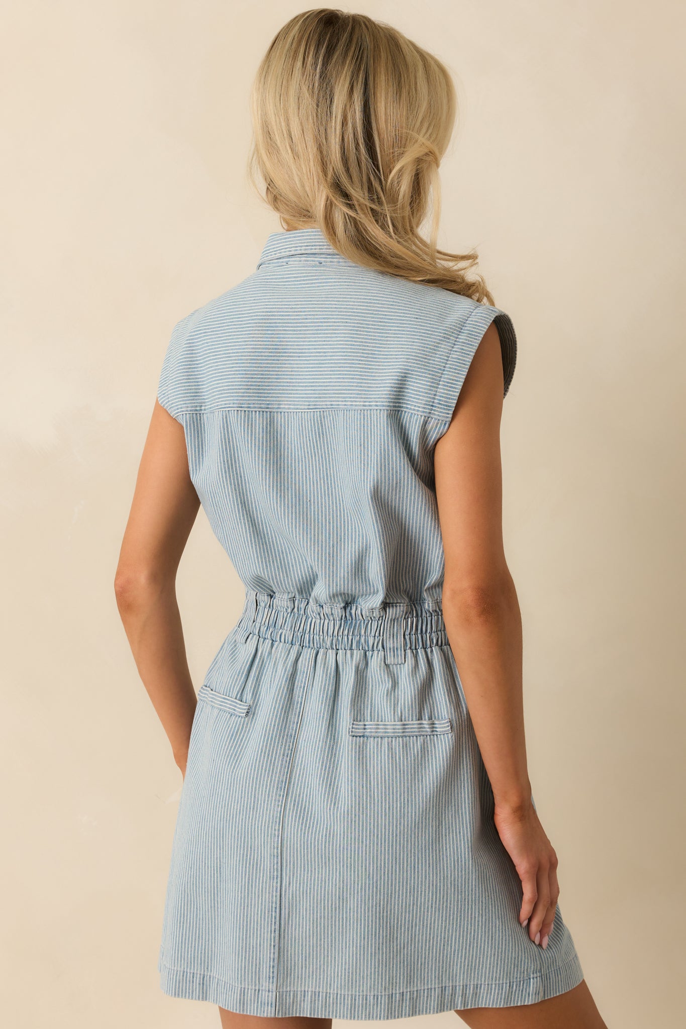 A back view of the light wash denim mini dress showing the pinstripe pattern and elastic waist.