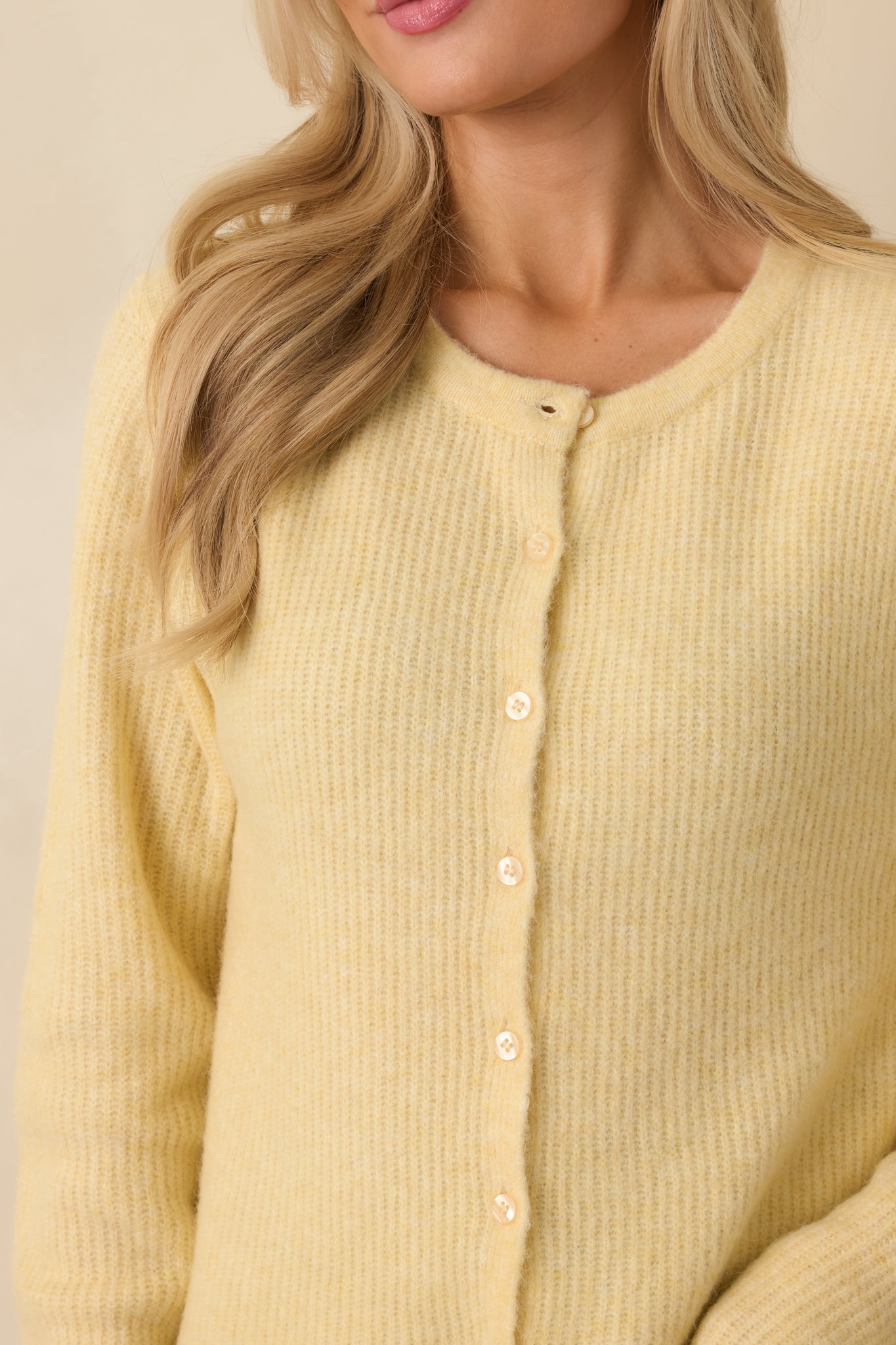 Detailed view of the light yellow ribbed knit fabric showing the button-front closure and fine ribbed texture.