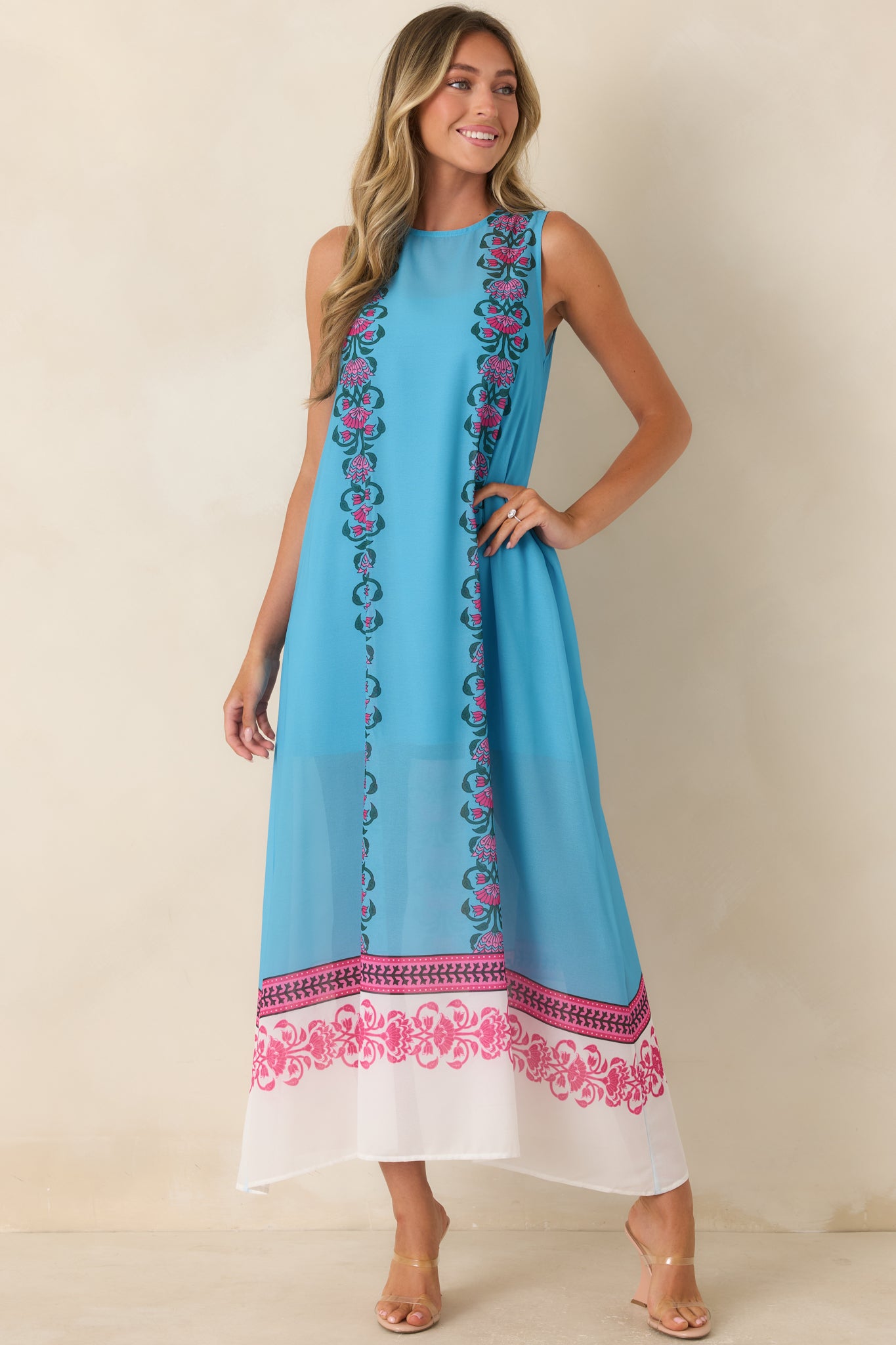 Lightweight blue maxi dress with vibrant floral border detailing, an elongated silhouette, and a relaxed fit designed for effortless movement.