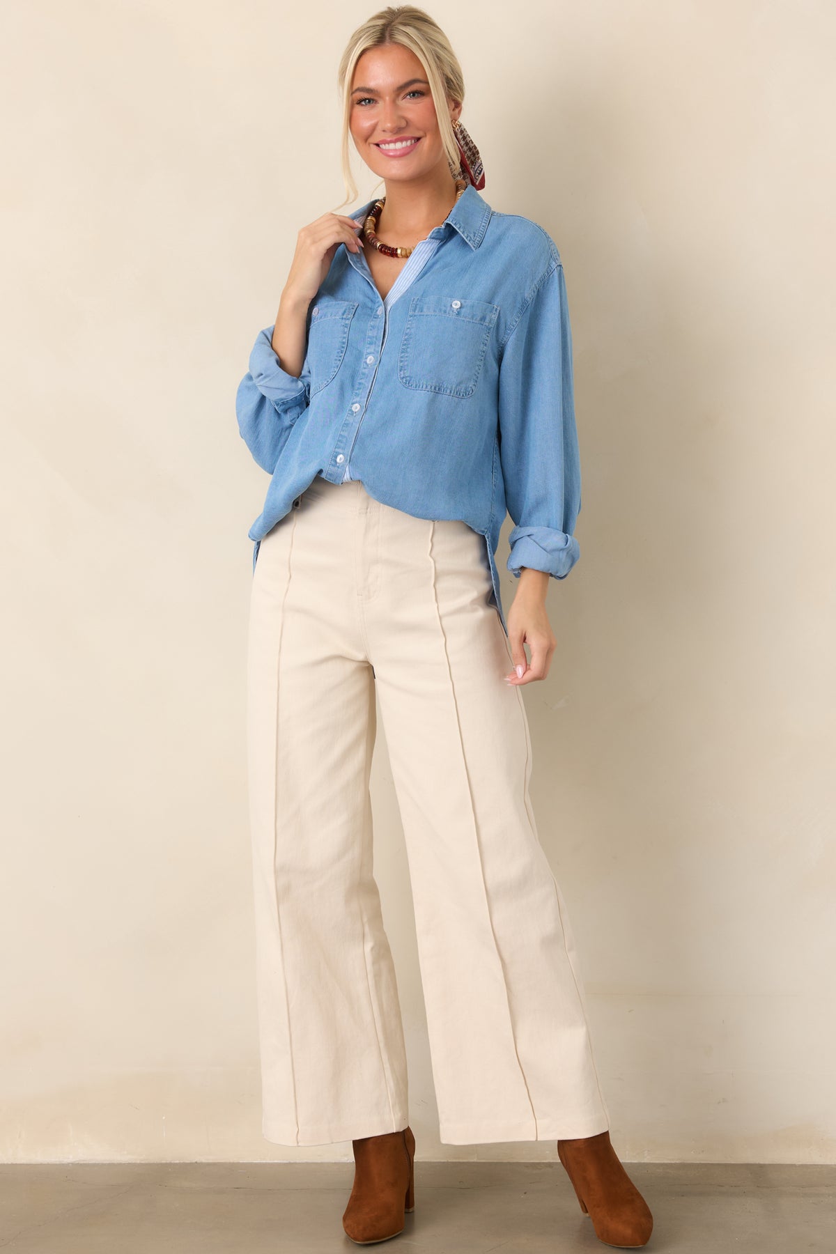 Lightweight denim shirt featuring a relaxed silhouette, pointed collar, chest patch pockets, subtle fading, and an elongated curved hem.