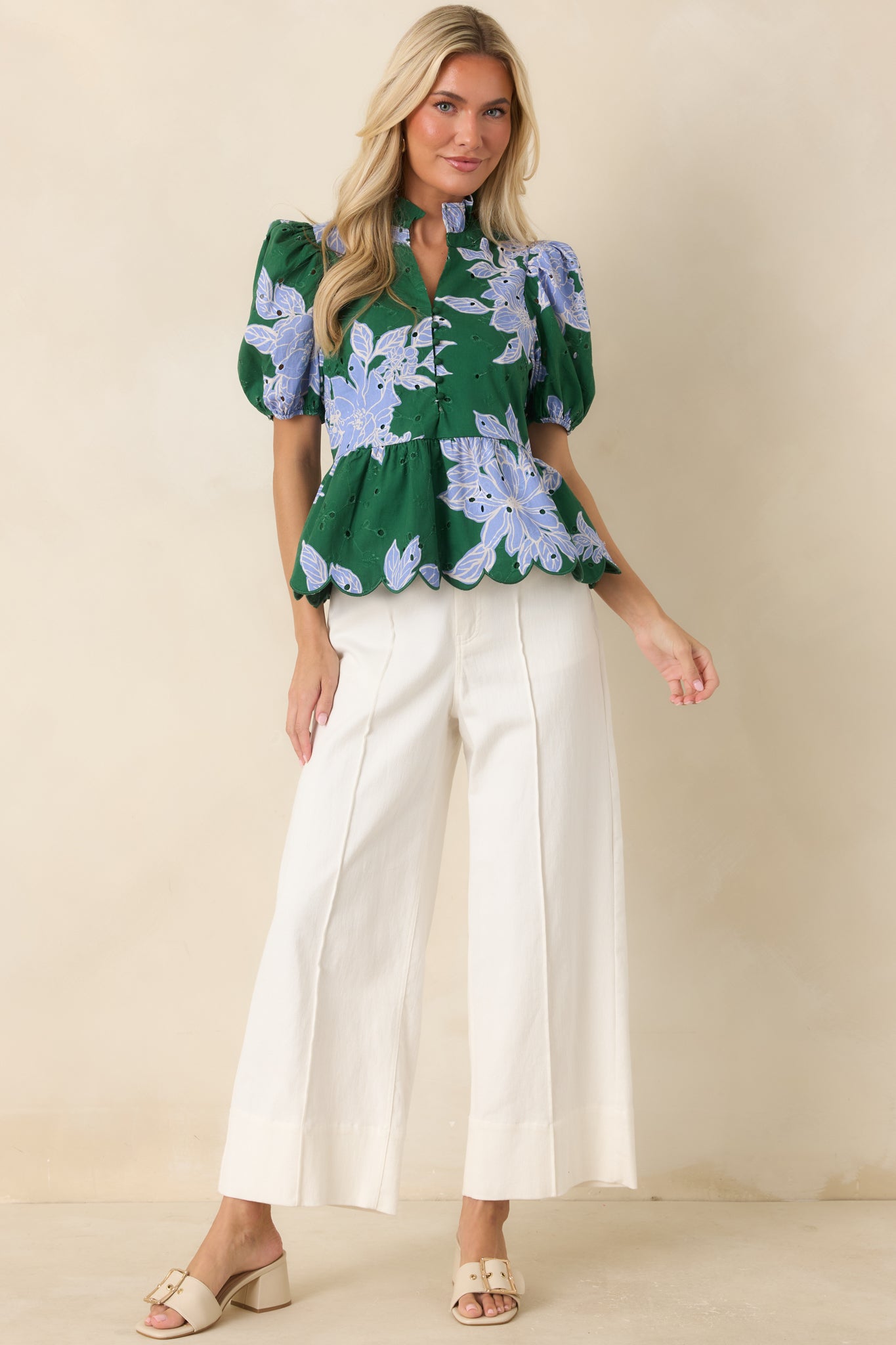 Lightweight floral blouse designed with eyelet embroidery, a button-front placket, puff sleeves, and a scalloped hemline.