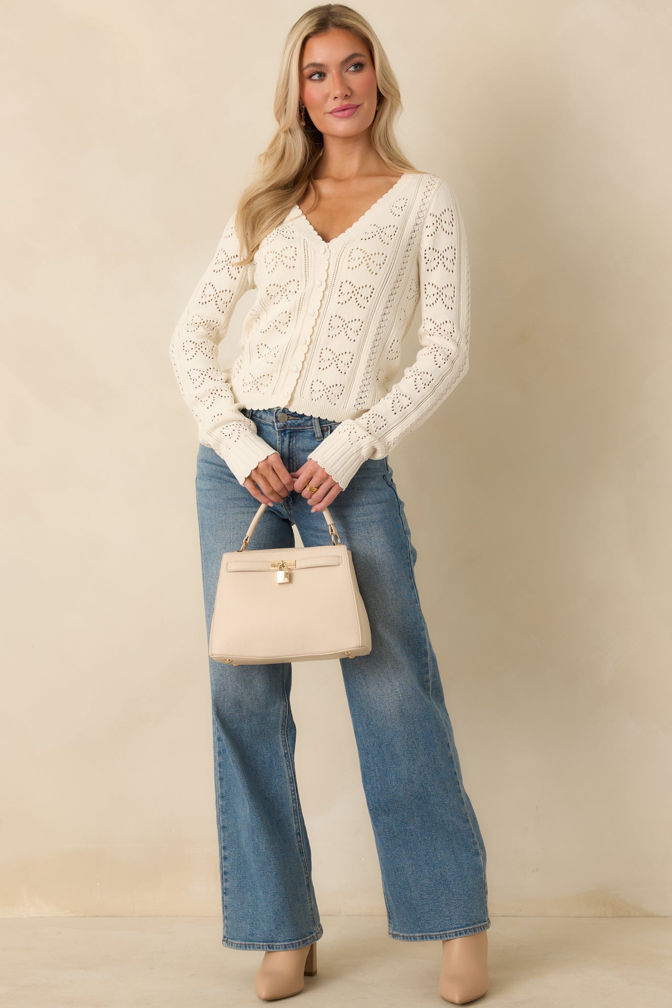 Lightweight ivory cardigan featuring long sleeves, subtle scalloped edges, and a slightly fitted silhouette.