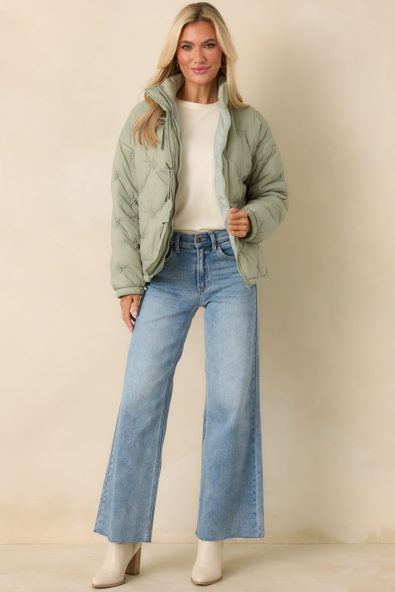 Lightweight sage green puffer jacket featuring long sleeves, elasticized cuffs, and subtle tie accents along the front.