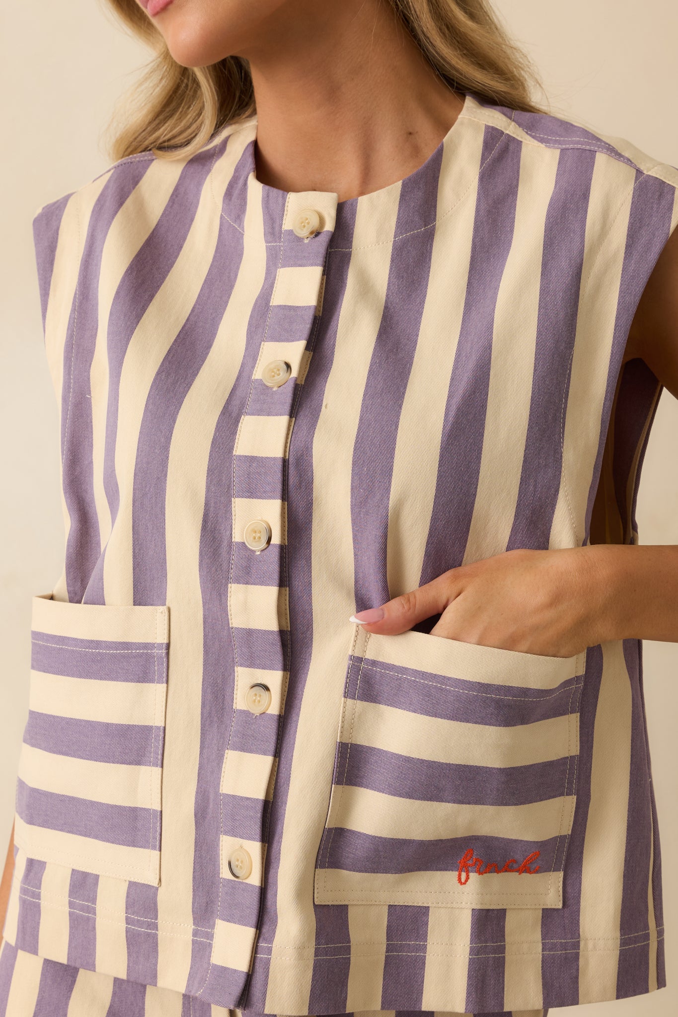 Detailed view of the vest’s front button and pocket area, highlighting the texture of the lilac and cream striped cotton.