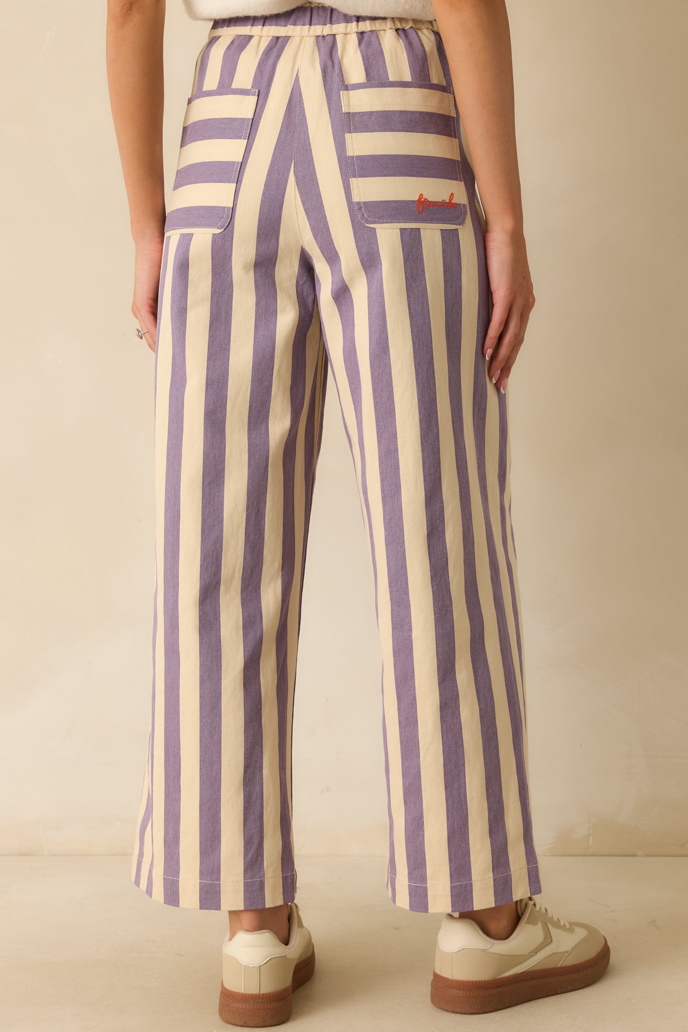 Rear view of the lilac striped pants showing the wide-leg flow and continuous vertical stripe pattern.