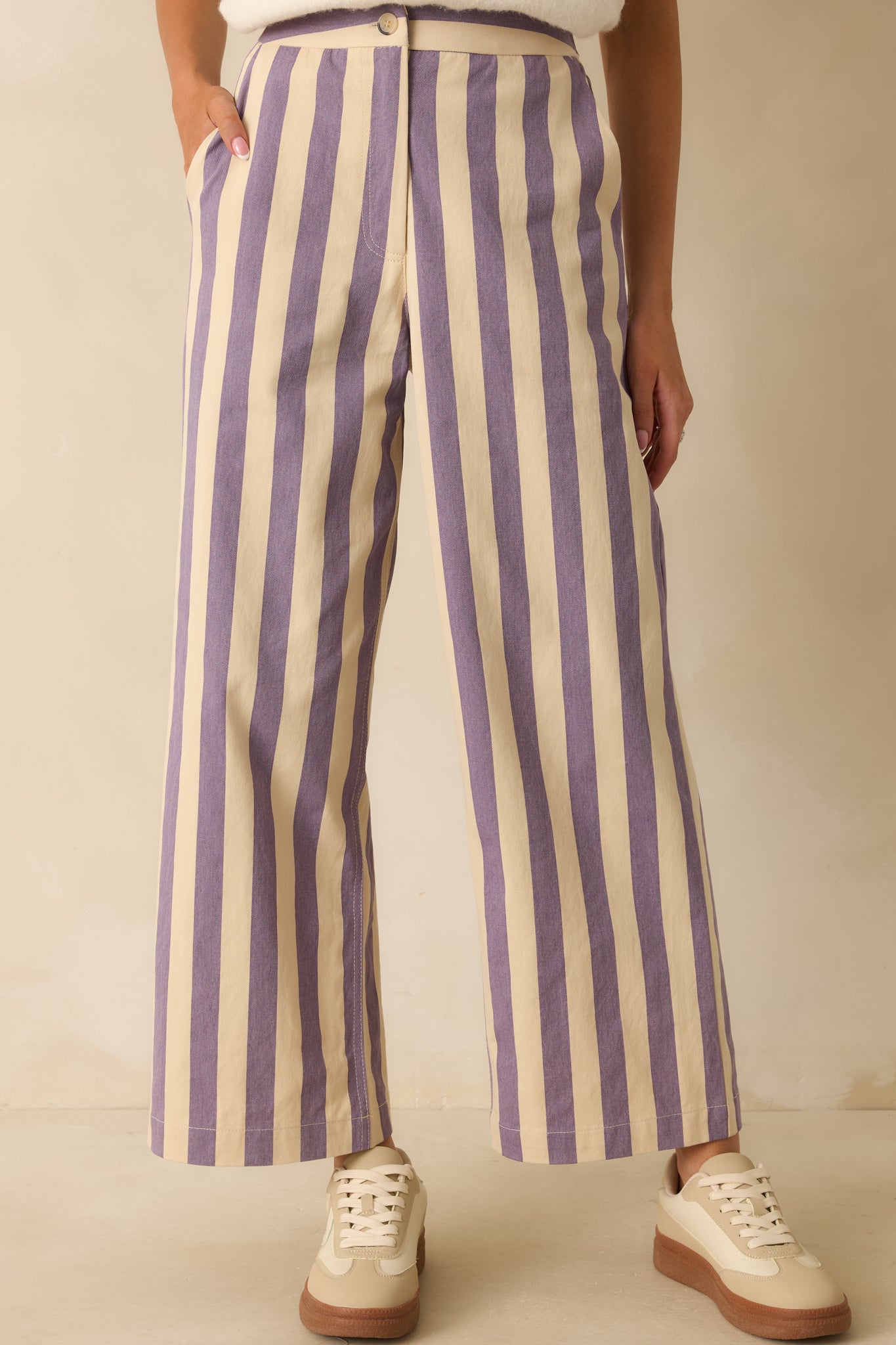 Close view of the waistband and button closure of the lilac striped pants, emphasizing their neat tailoring.