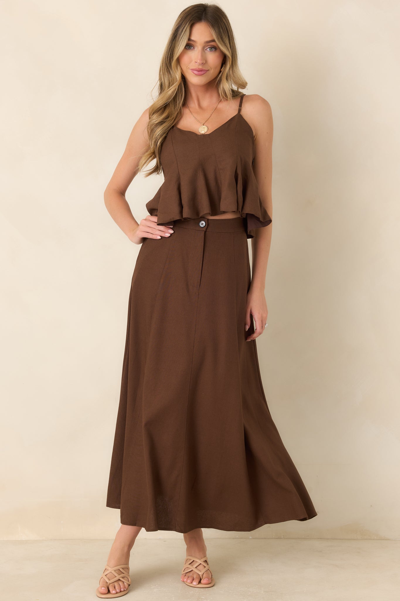 Linen and cotton blend peplum top featuring a softly shaped neckline, adjustable spaghetti straps, paneled seaming, and a flared hem.