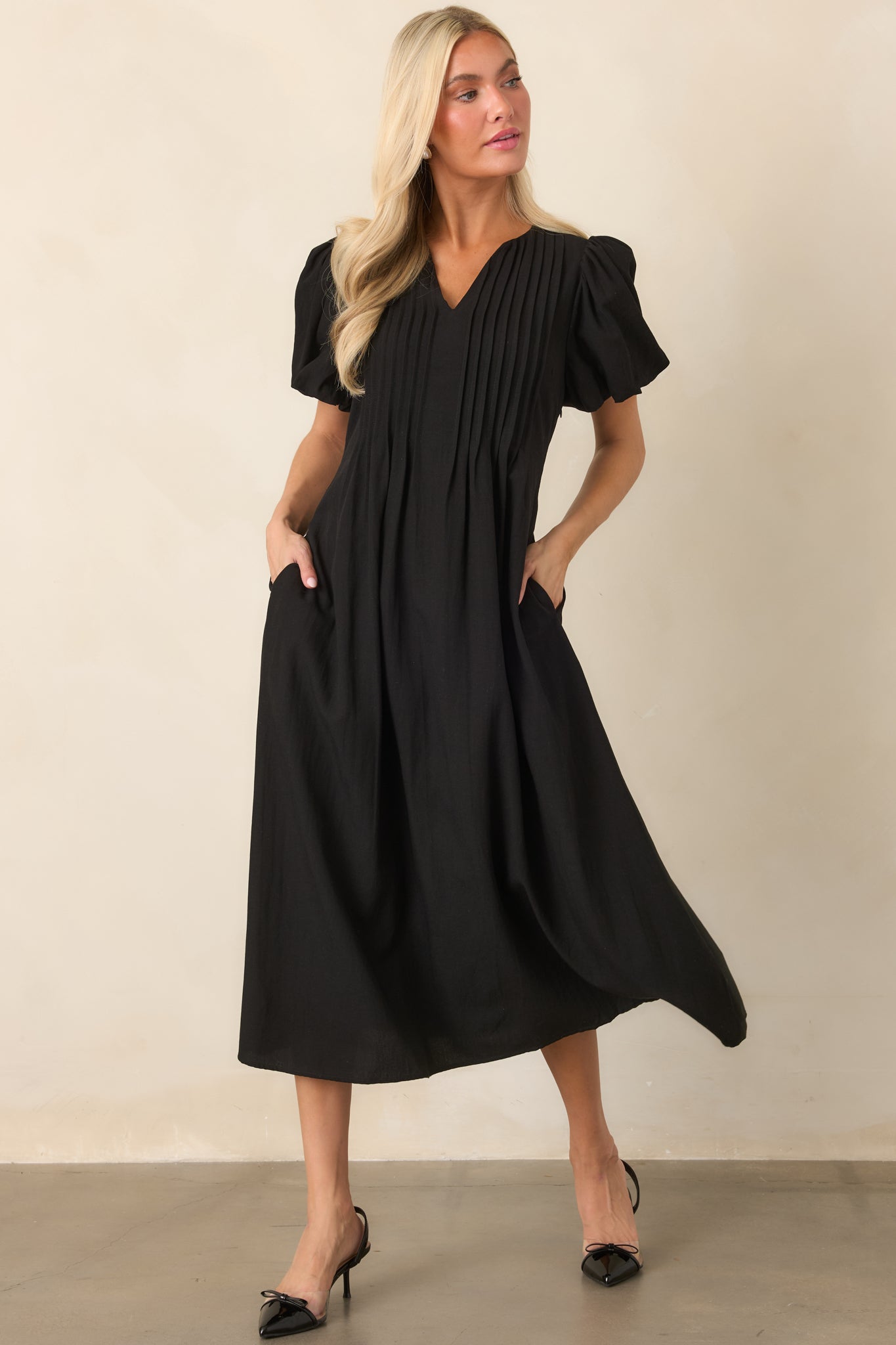 Linen-textured midi dress with a graceful flowing skirt, V-neckline, puff sleeves, and neatly defined pintuck detailing across the bodice.