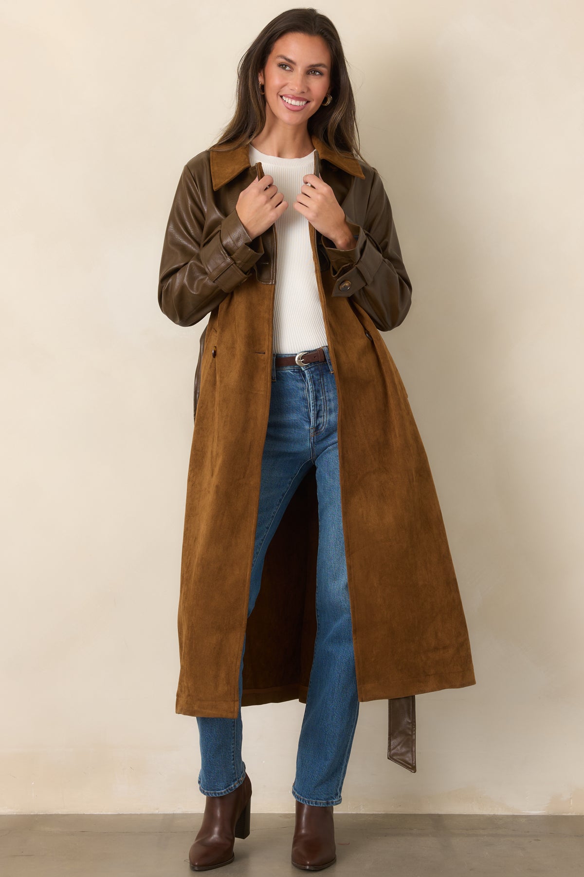Long caramel trench coat featuring brown faux leather sleeves, a double-breasted front, and a coordinating tie belt.